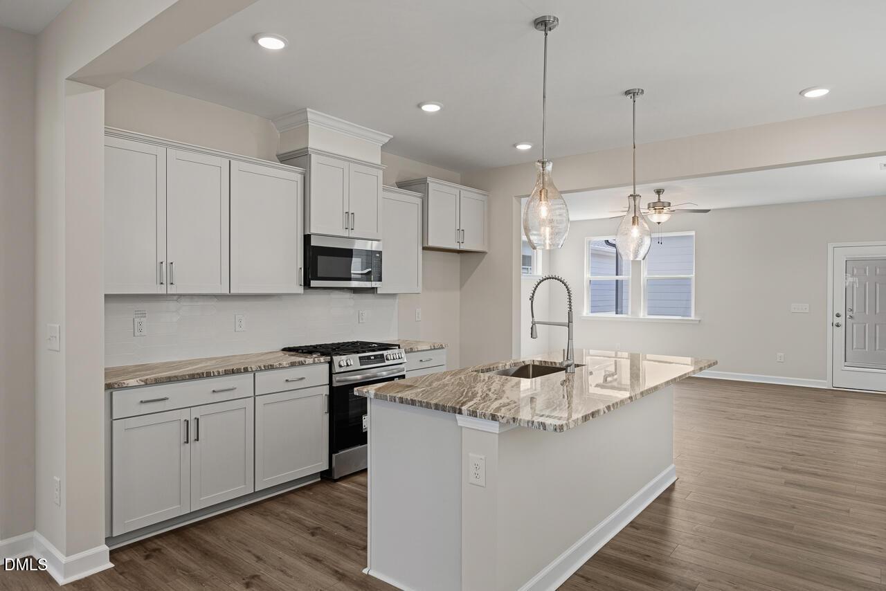 Modern kitchen with granite island and light gray cabinetry in The Alexander C floor plan, Forestville Yard, Knightdale, NC.