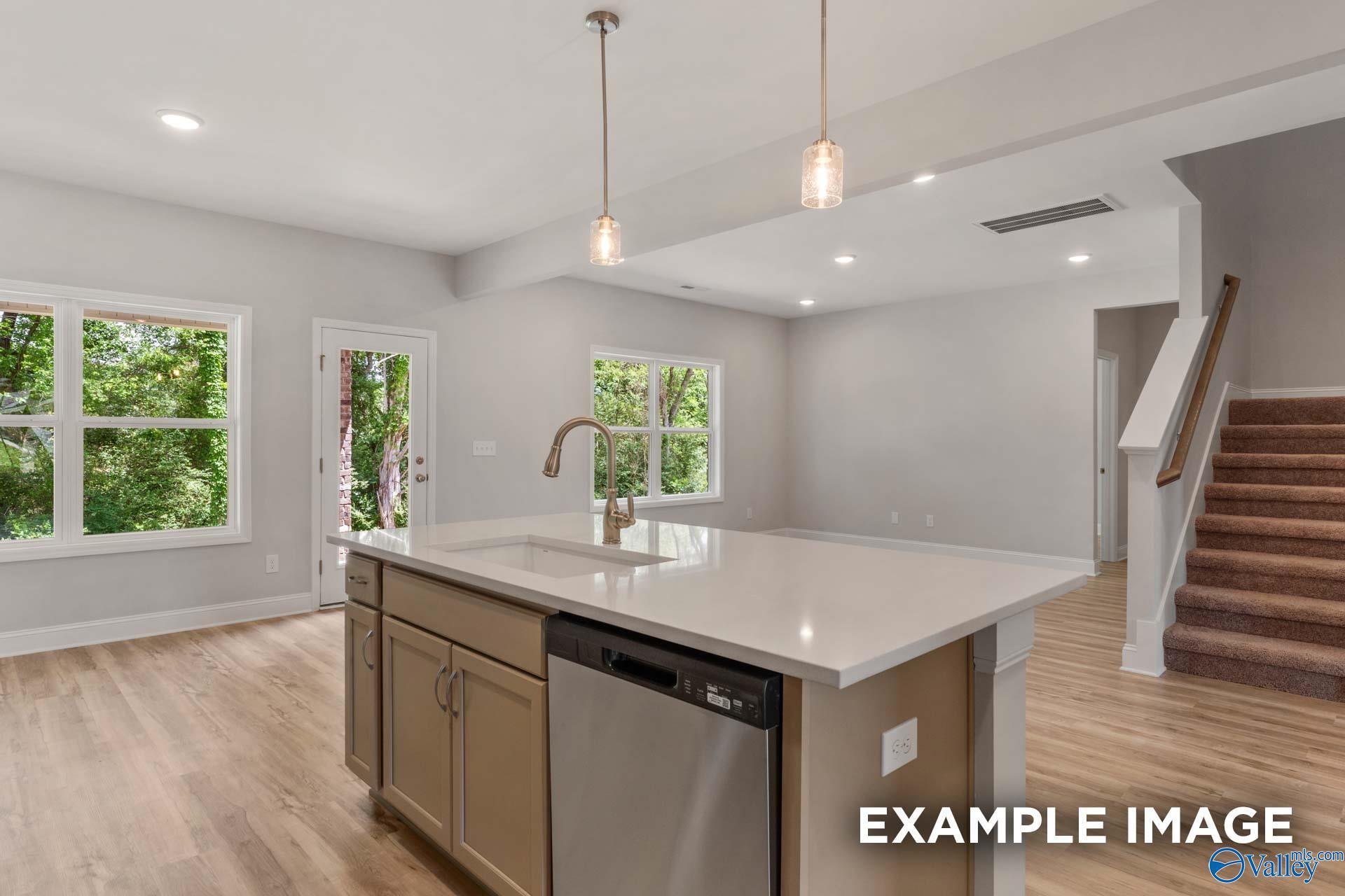 Open-concept kitchen with quartz island, stainless dishwasher, shaker cabinets, and garden-view windows in The Shelby C, Meridianville, AL