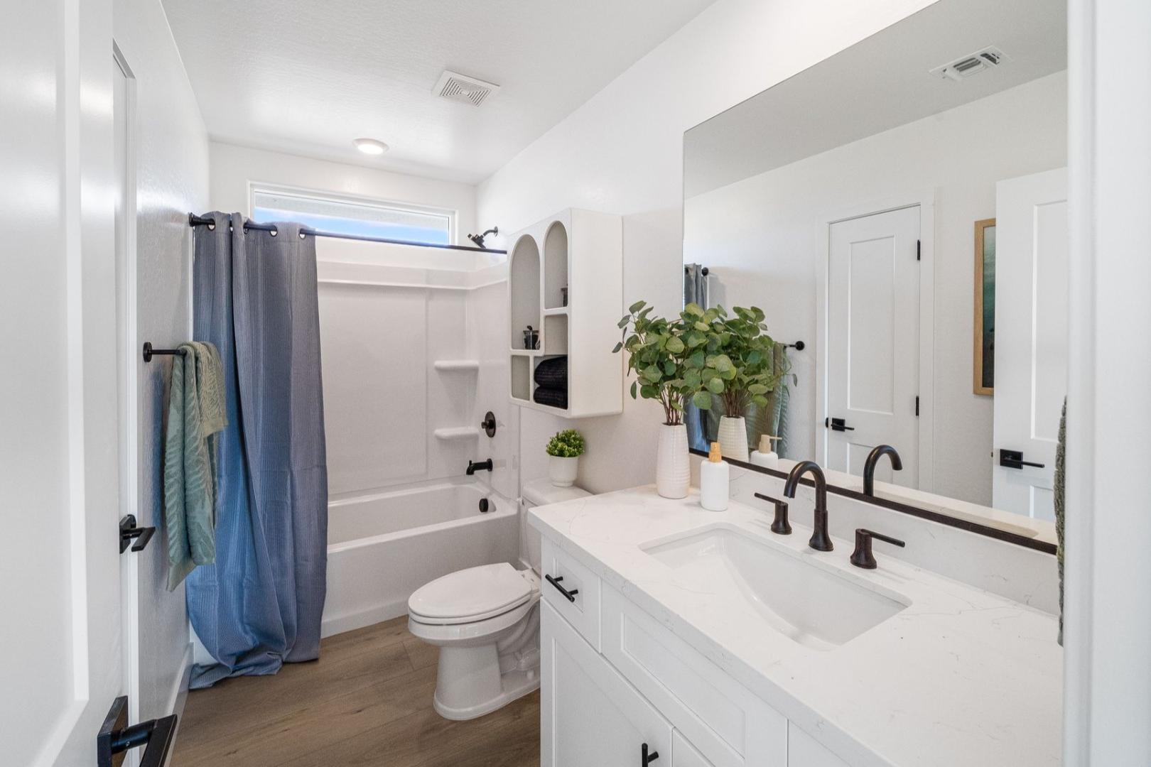 Spacious master bathroom in The Wilmington A by Davidson Homes: white vanity, soaking tub with blue curtain, potted plants