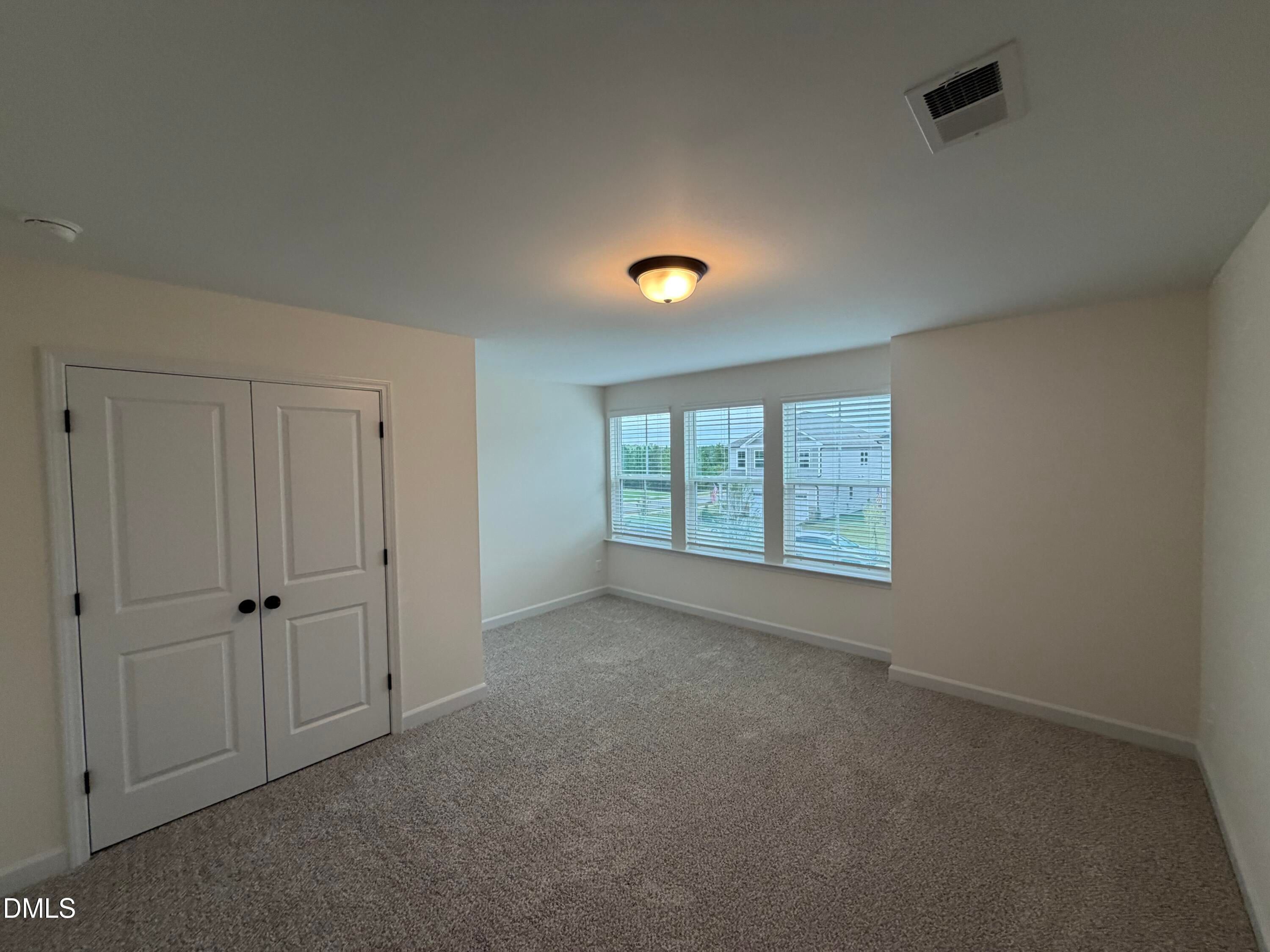 Bright carpeted bedroom with white double-door closet and blinds in Davidson Homes The Ashport M, Wendell Ridge, NC