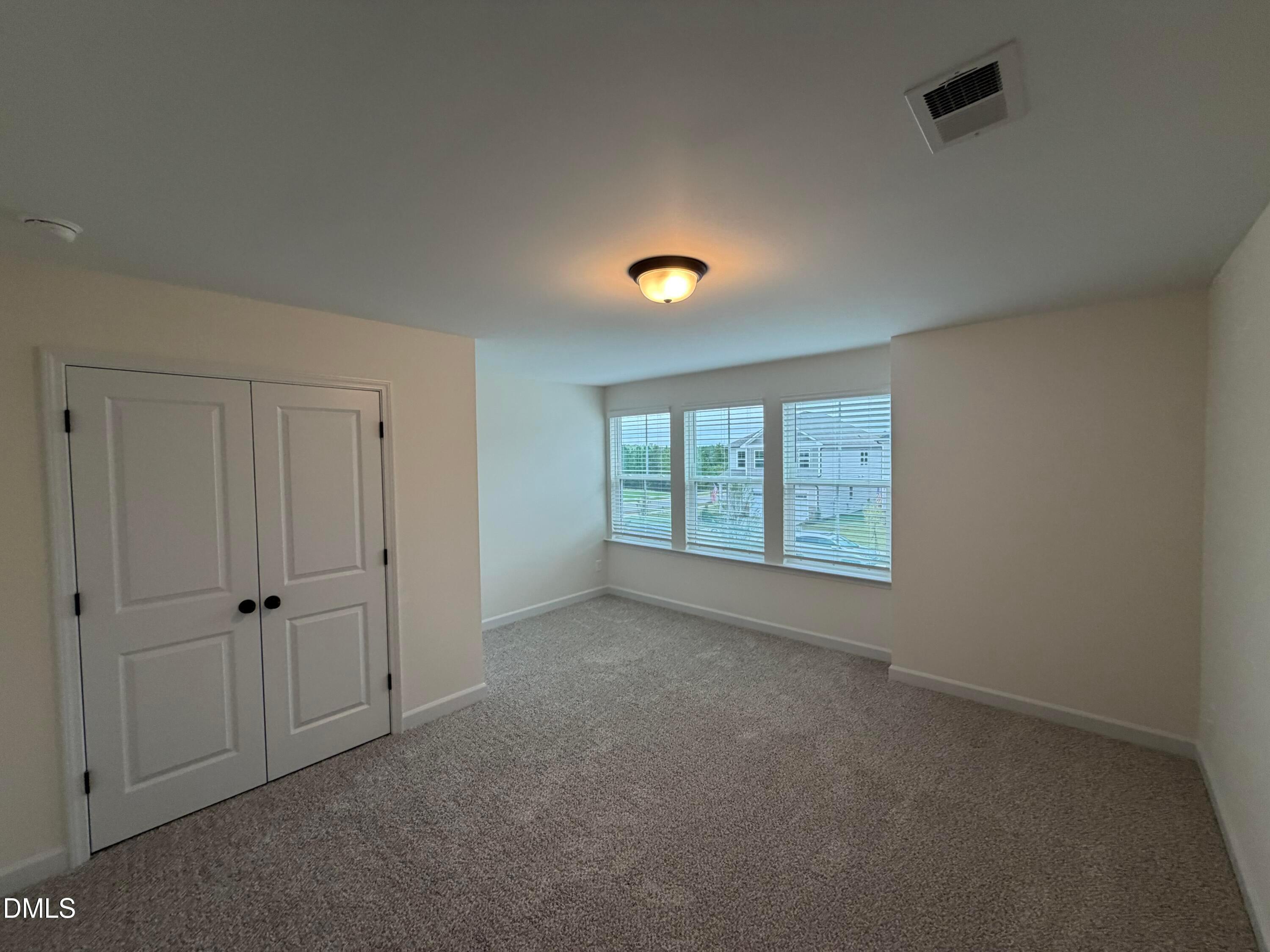 Bright carpeted bedroom with white double-door closet and blinds in Davidson Homes The Ashport M, Wendell Ridge, NC