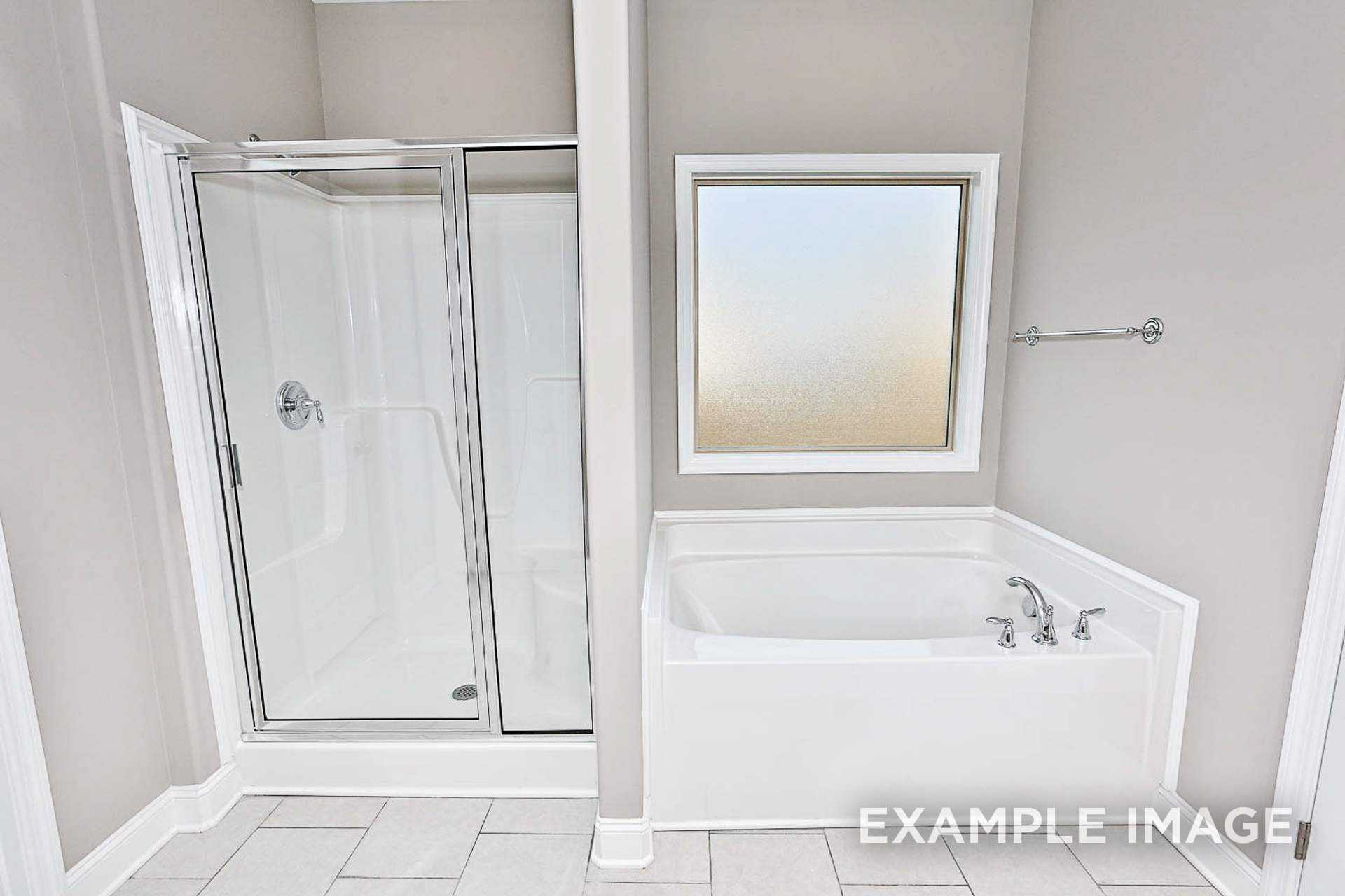 Spacious master bathroom in The Montgomery B featuring glass shower enclosure, corner soaking tub, and frosted window
