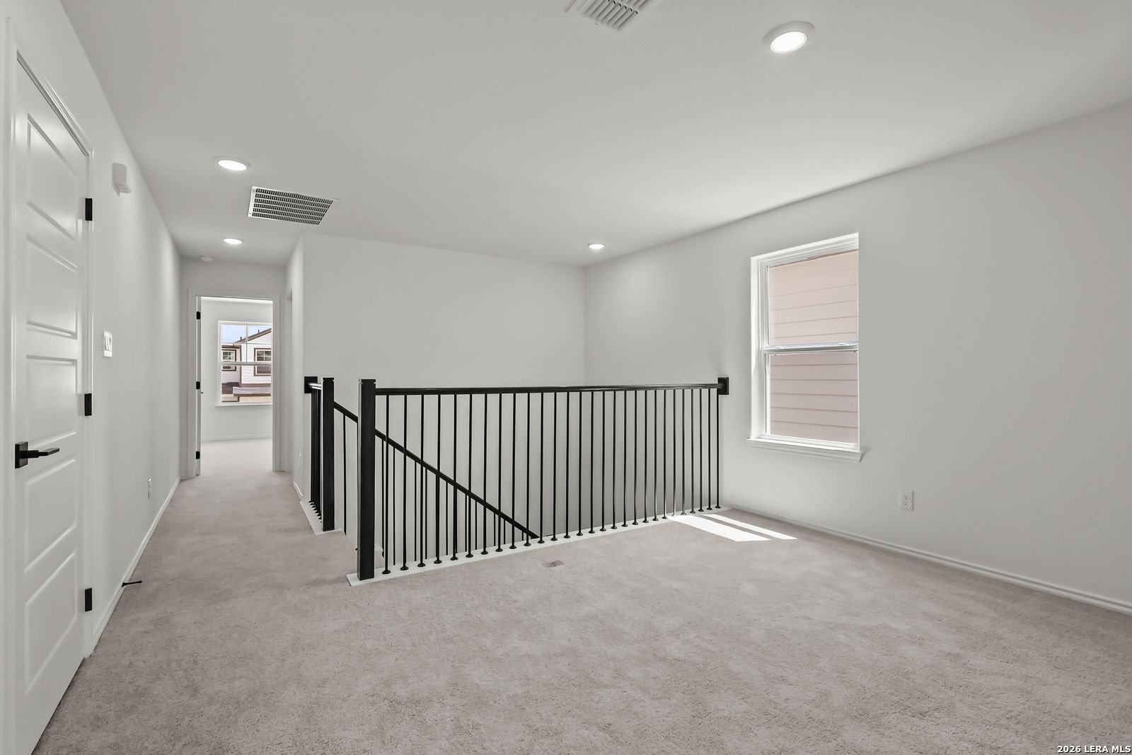 Spacious carpeted upstairs loft with black iron railing in The Florence B floor plan at Meadows at Oak Creek, San Antonio.