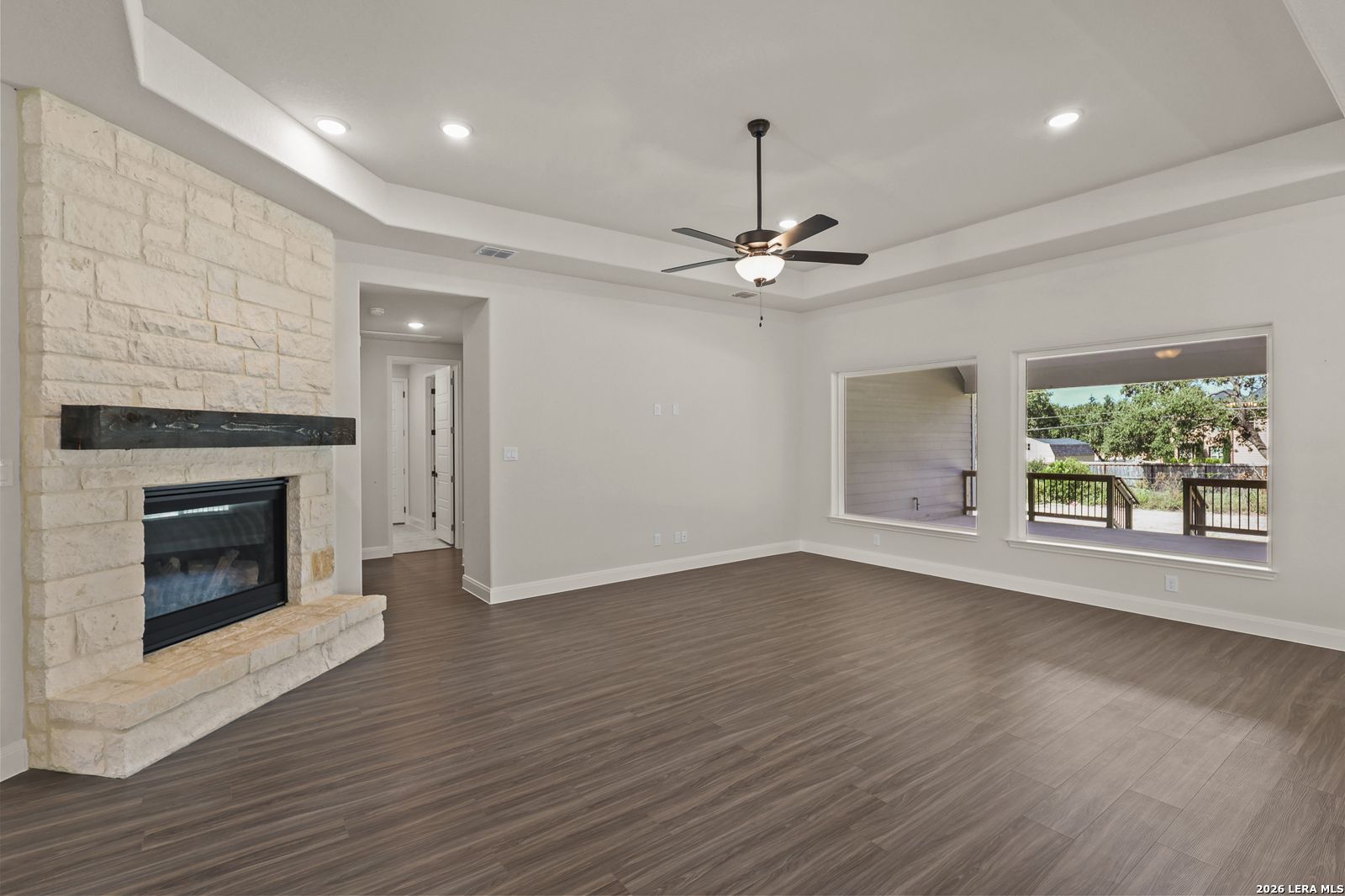 Spacious living room with stone fireplace and tray ceiling in The Summerlin B floor plan, Potranco Oaks, Castroville, TX.
