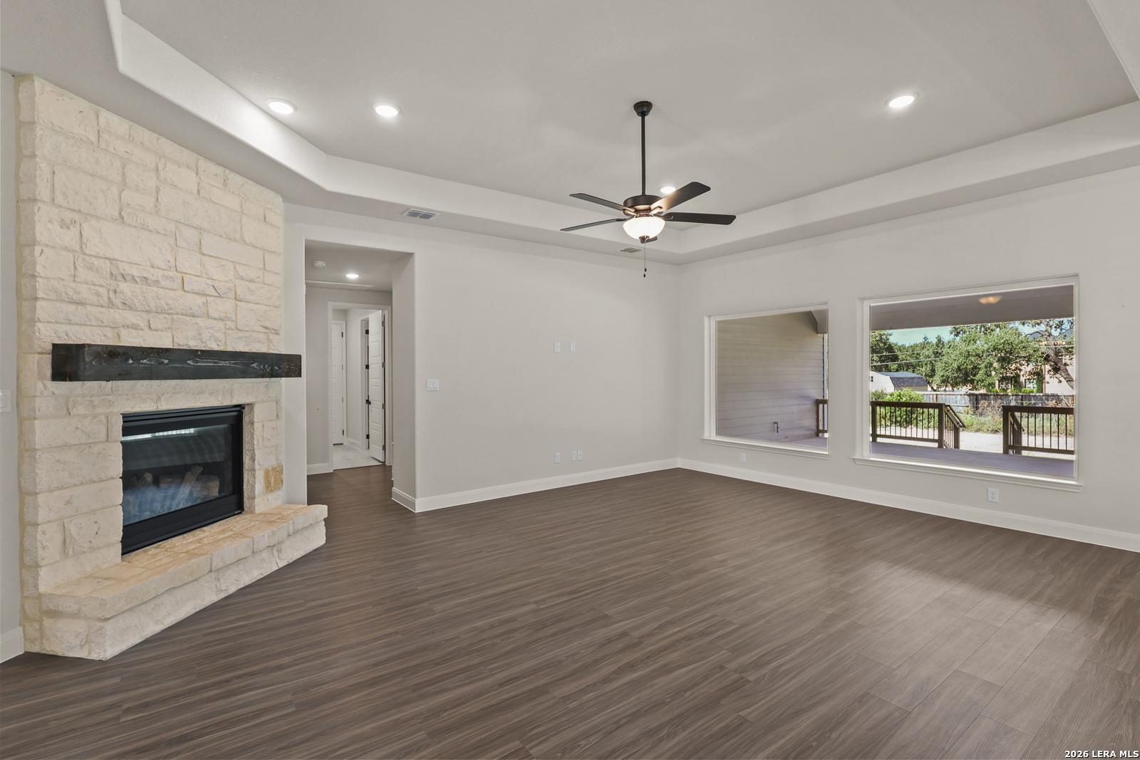 Spacious living room with stone fireplace and tray ceiling in The Summerlin B floor plan, Potranco Oaks, Castroville, TX.