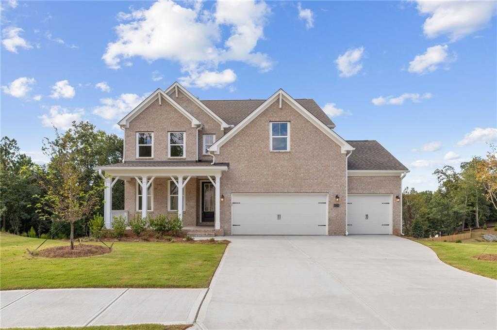 Two-story brick home with covered front porch and 3-car garage, landscaped yard in Melody Lakeside Estates, Buford, Georgia