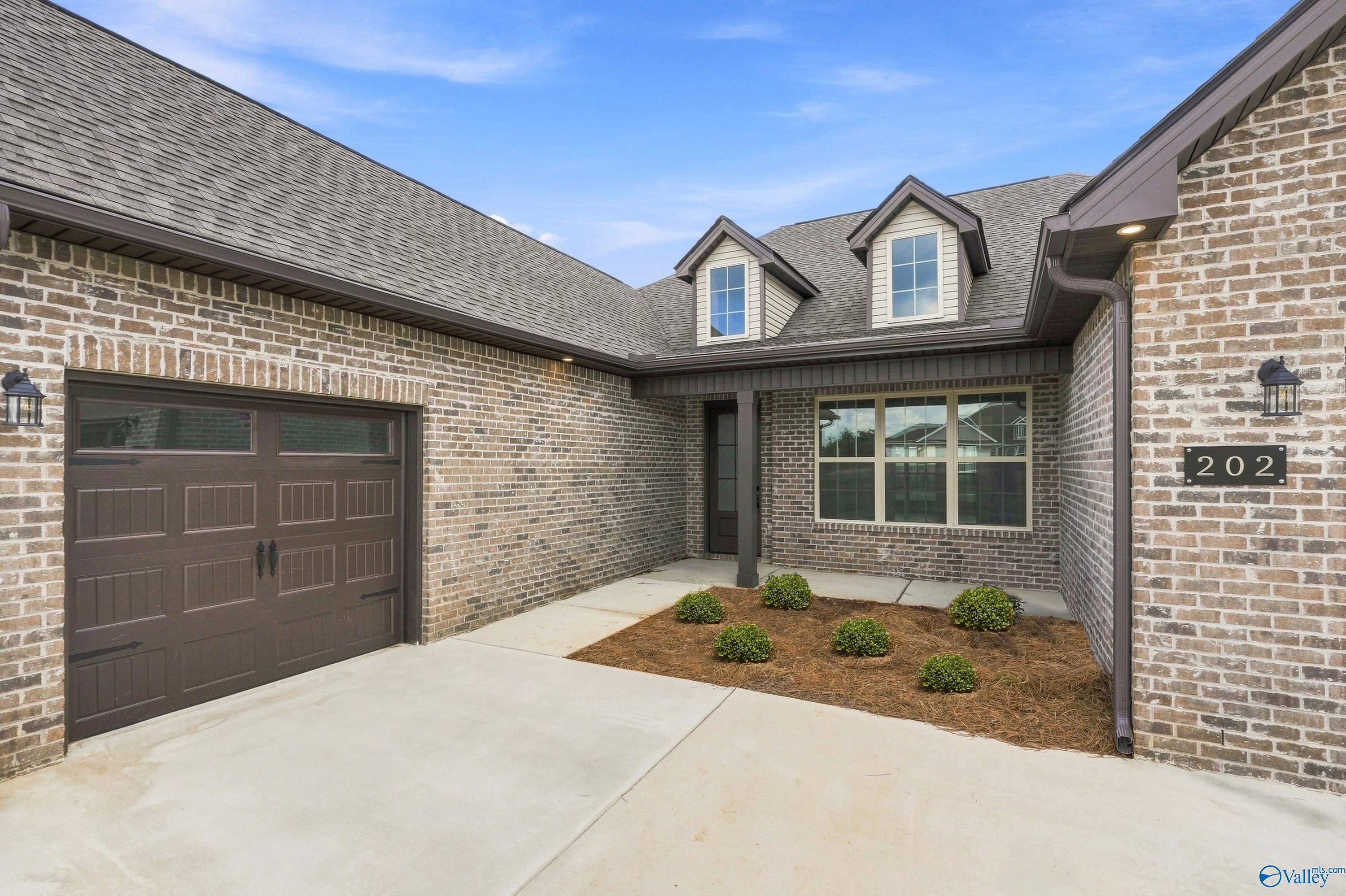 Brick exterior of The Valencia by Davidson Homes with 3-car garage and landscaped yard in Riverton Preserve, Huntsville, Alabama.