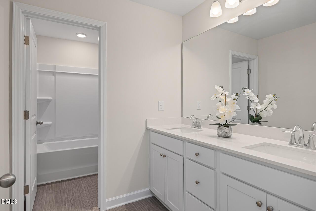 Elegant master bathroom featuring double vanity, soaking tub, walk-in shower, and orchids in Davidson Homes Preston A, Lillington NC