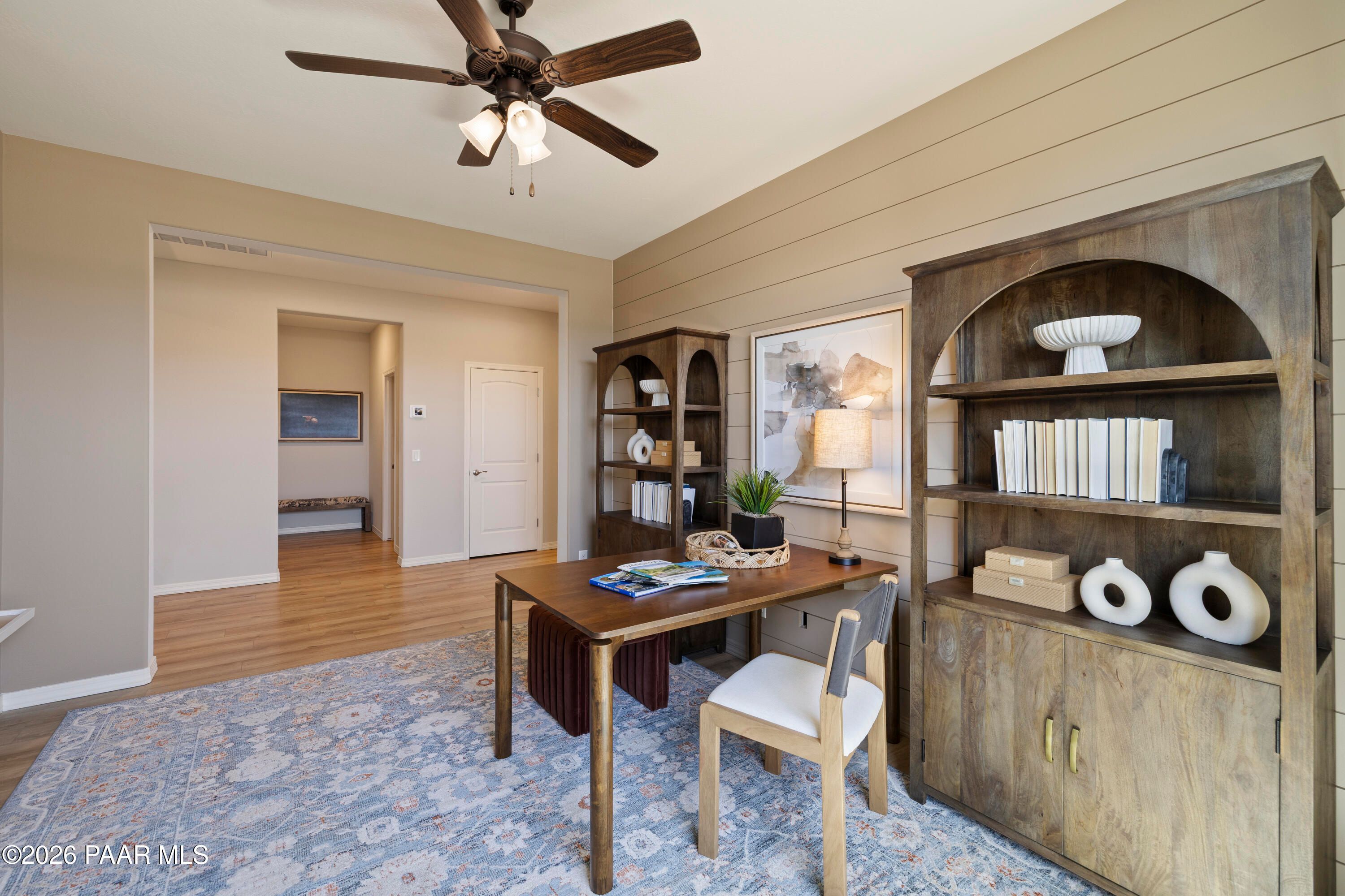 Home office with shiplap wall, wooden desk, and bookshelves in The Harmony A floor plan at North Ridge, Prescott Valley.