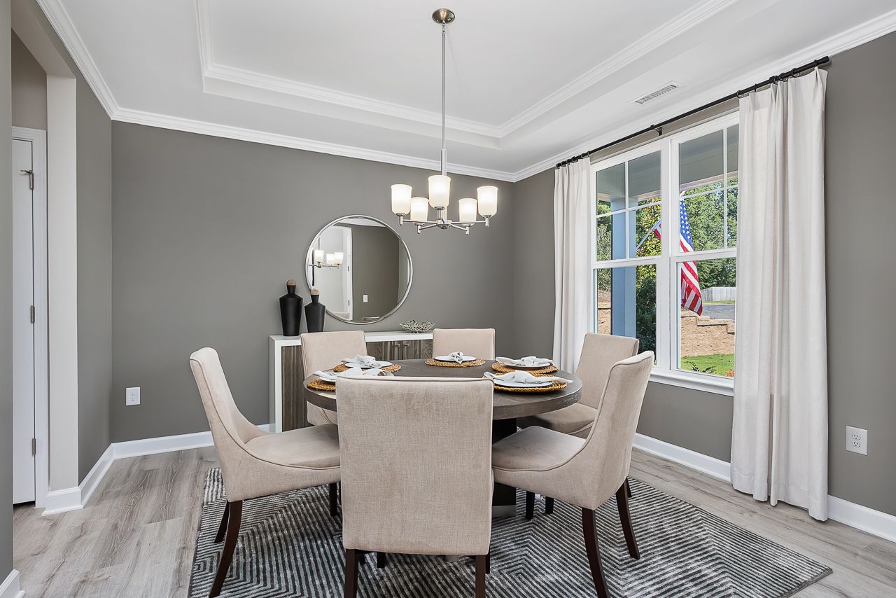 Modern dining room at Woodland Crossing in Zebulon, NC by Davidson Homes featuring round table and tray ceiling.