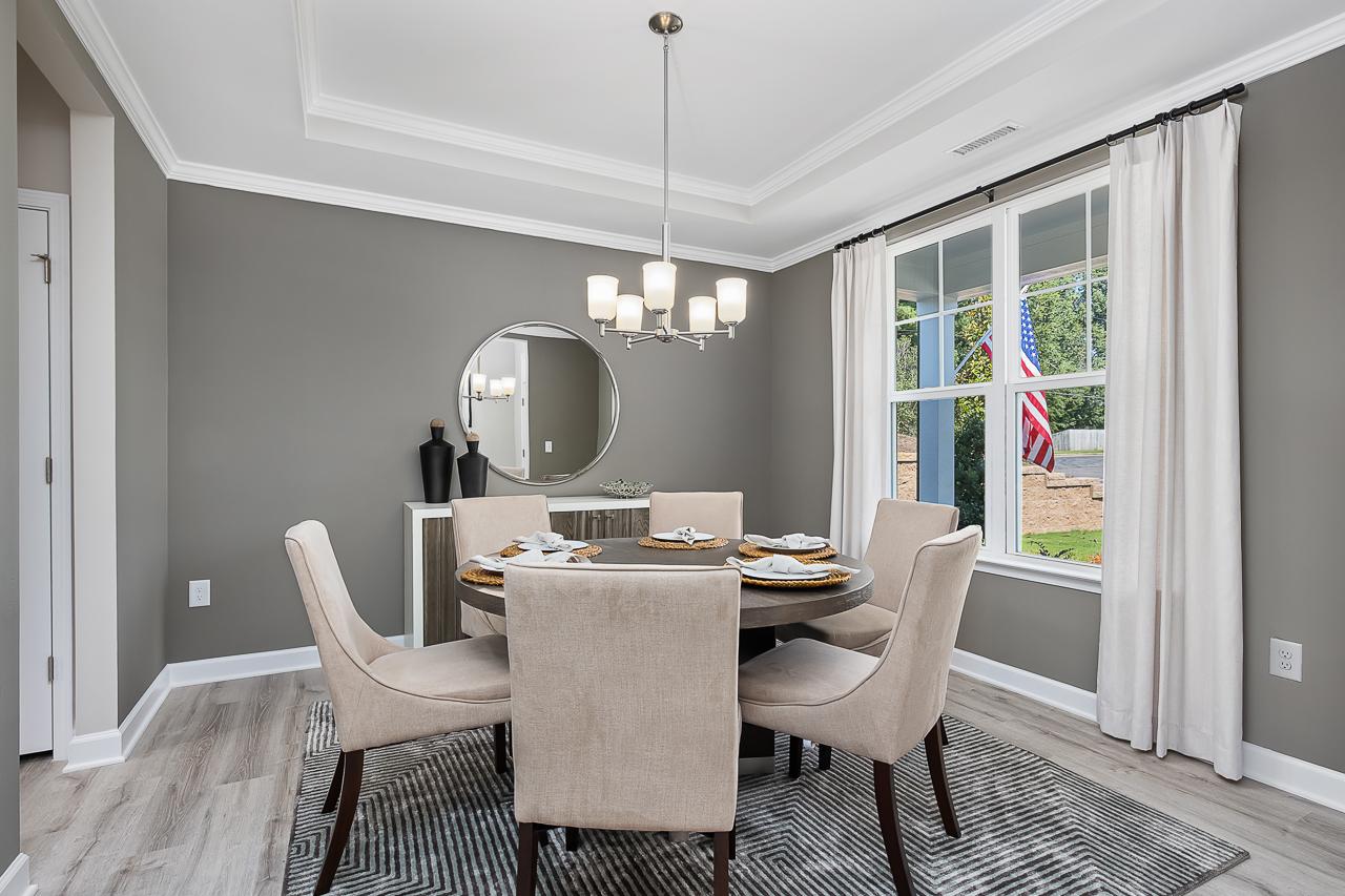 Modern dining room at Woodland Crossing in Zebulon, NC by Davidson Homes featuring round table and tray ceiling.