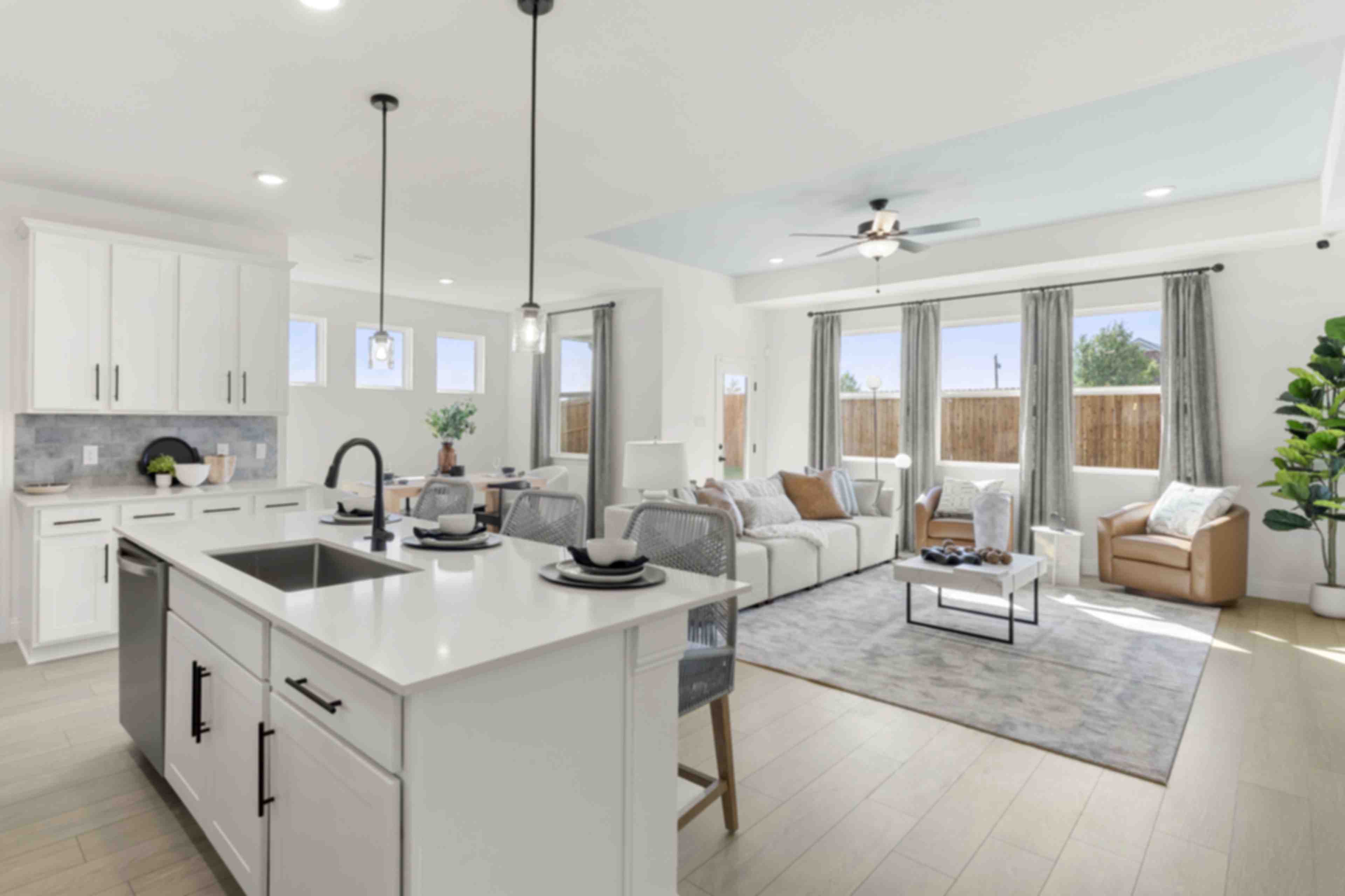 Open-concept living room at Meadow Ridge Estates in Josephine Texas with light wood floors gray sectional sofa ceiling fan and potted plant
