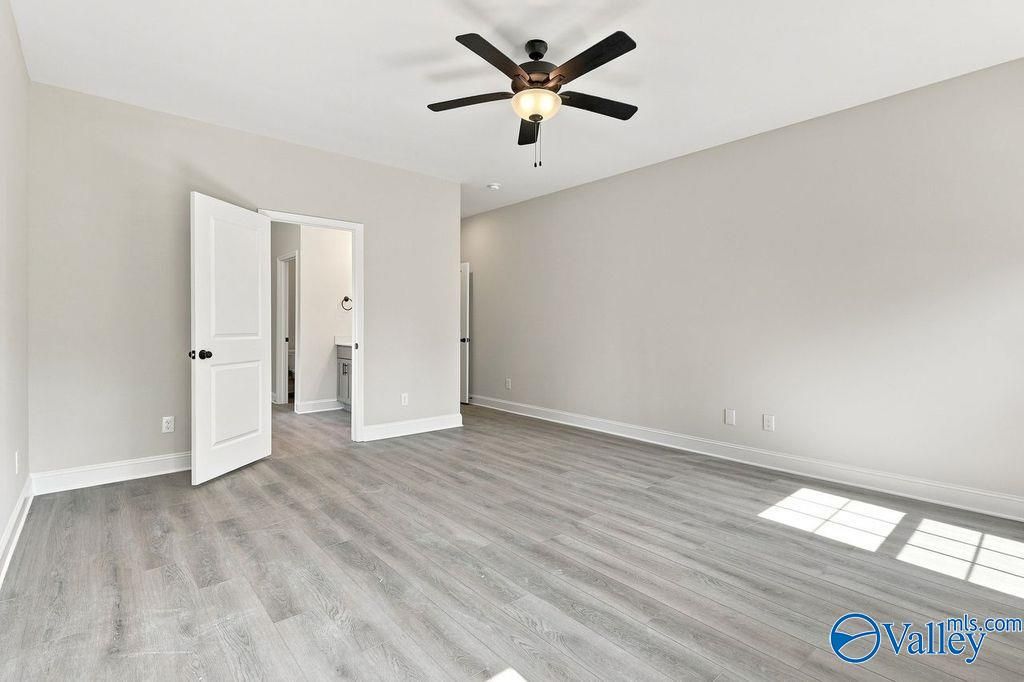 Spacious primary bedroom with luxury vinyl plank flooring and ceiling fan in Davidson Homes Rockford plan, Cain Park, Hartselle