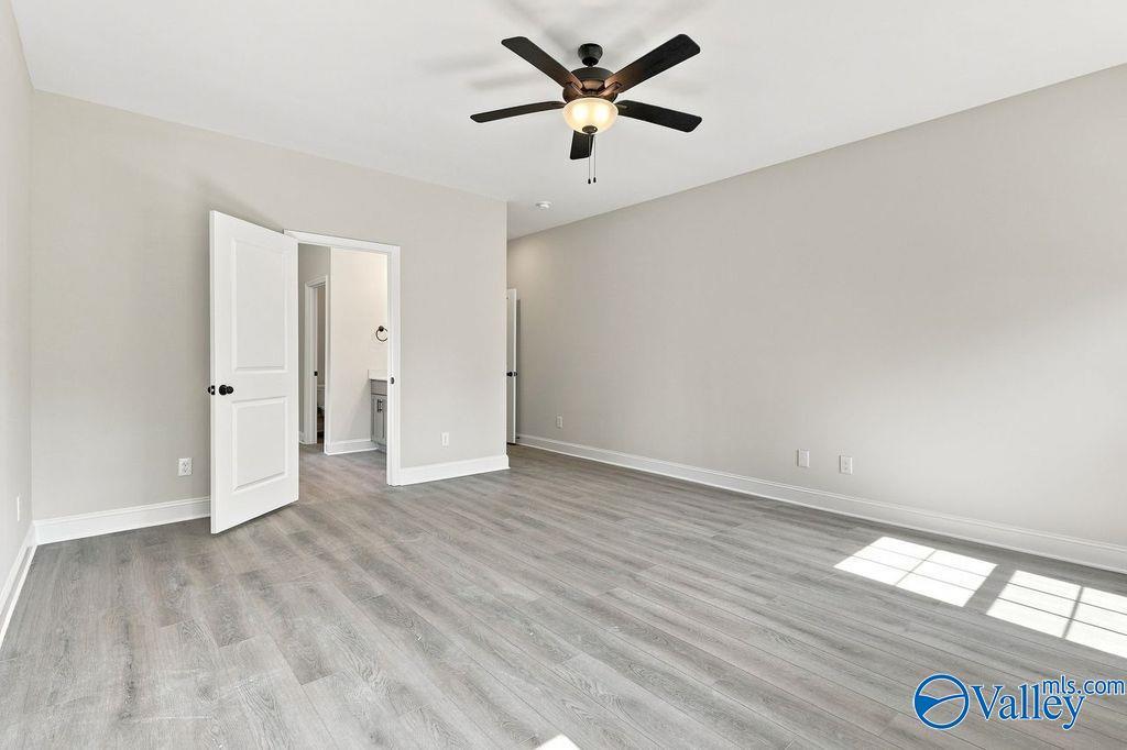 Spacious primary bedroom with luxury vinyl plank flooring and ceiling fan in Davidson Homes Rockford plan, Cain Park, Hartselle