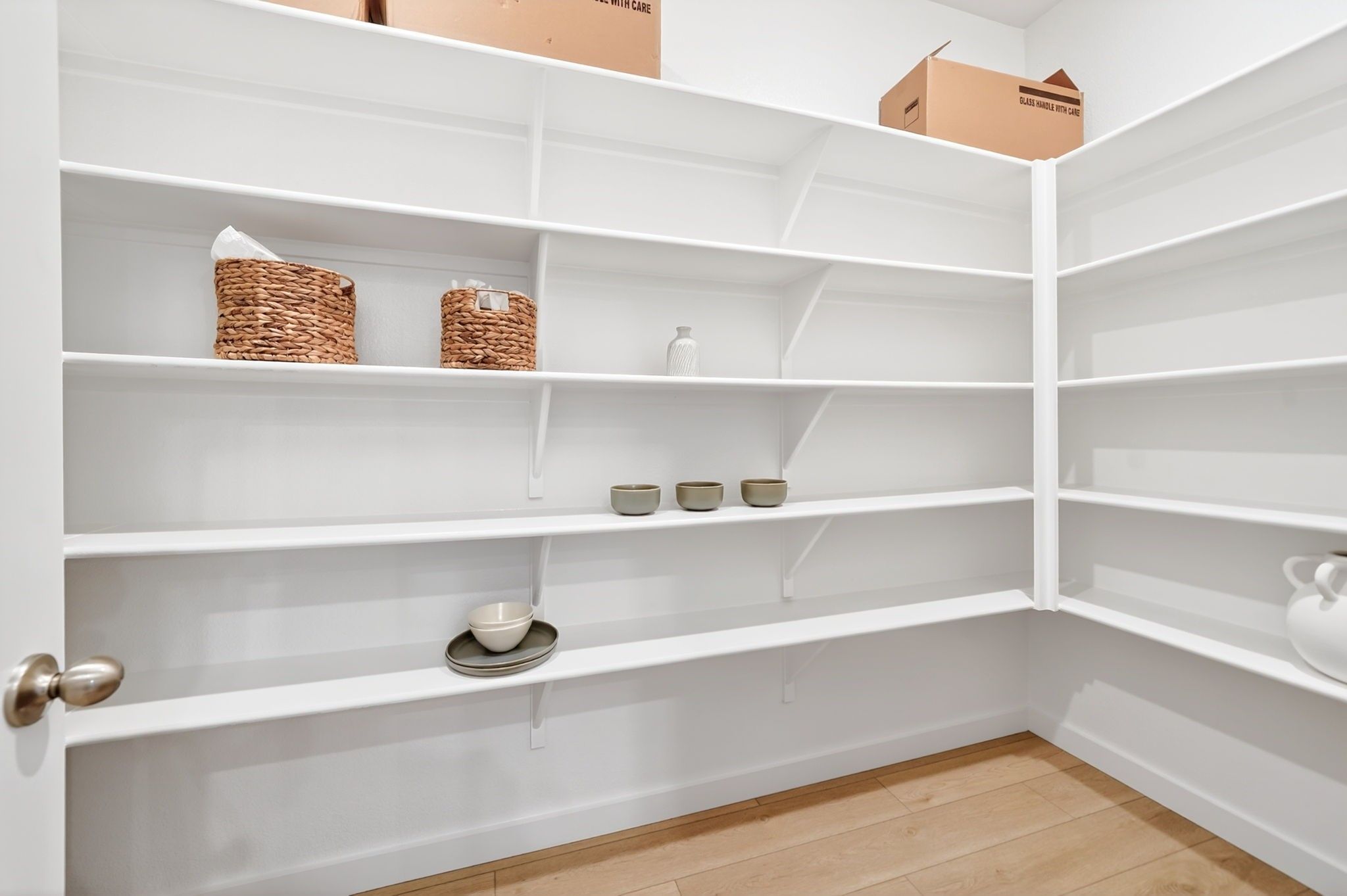 Spacious white walk-in pantry with abundant shelving in The Laurel M floor plan at Parks at Foster Crossing, Anna, Texas.