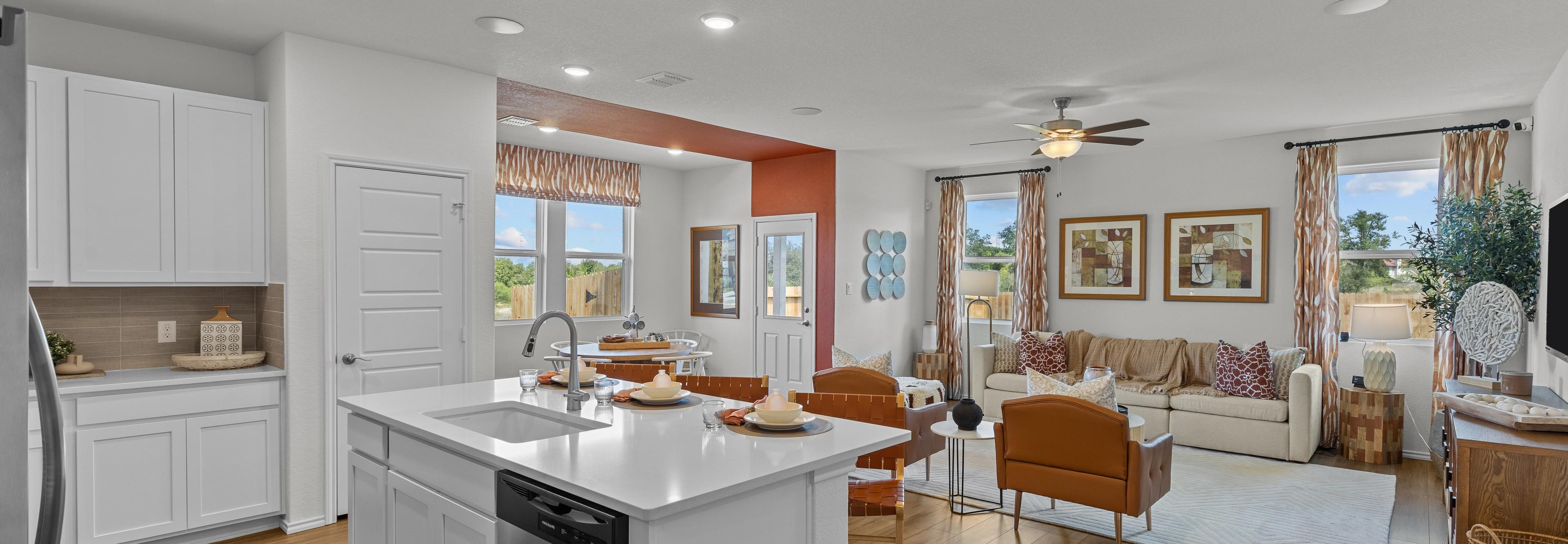 Open-concept kitchen and living room at Royal Crest in San Antonio TX by Davidson Homes with white island, hardwood floors