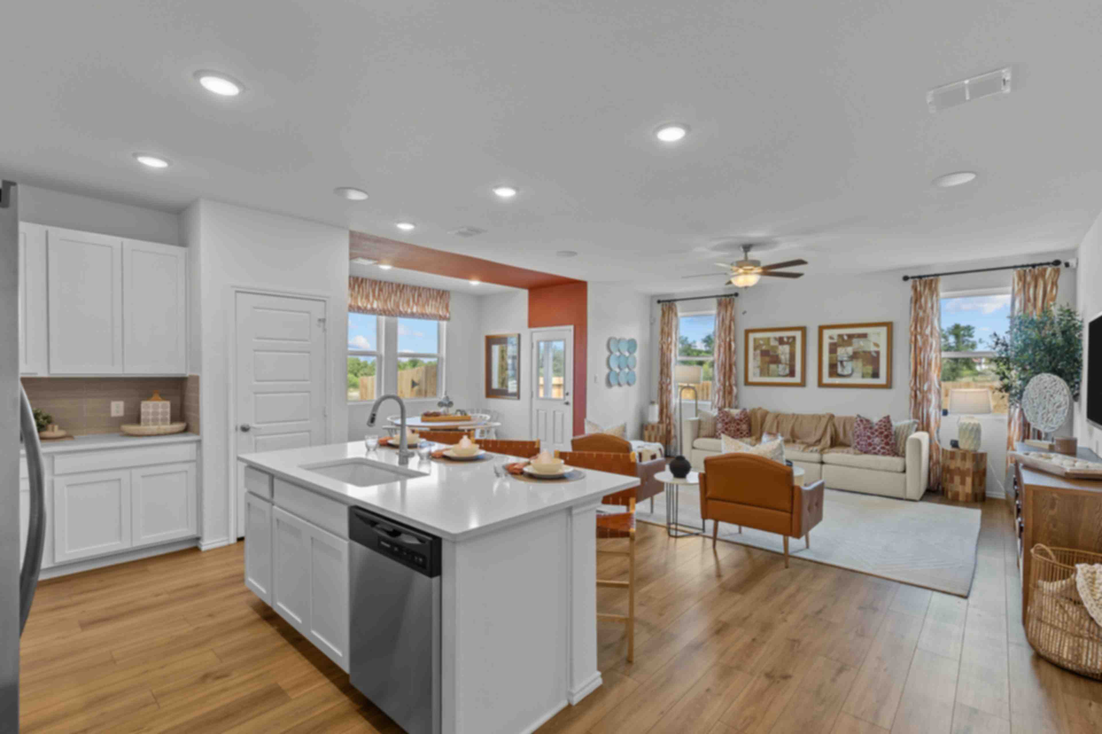 Open-concept kitchen and living room at Royal Crest in San Antonio TX by Davidson Homes with white island, hardwood floors