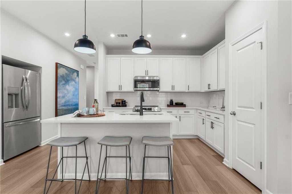 Modern white kitchen with island, stainless appliances, pendant lights in Davidson Homes The Durant A, Emerson, Georgia