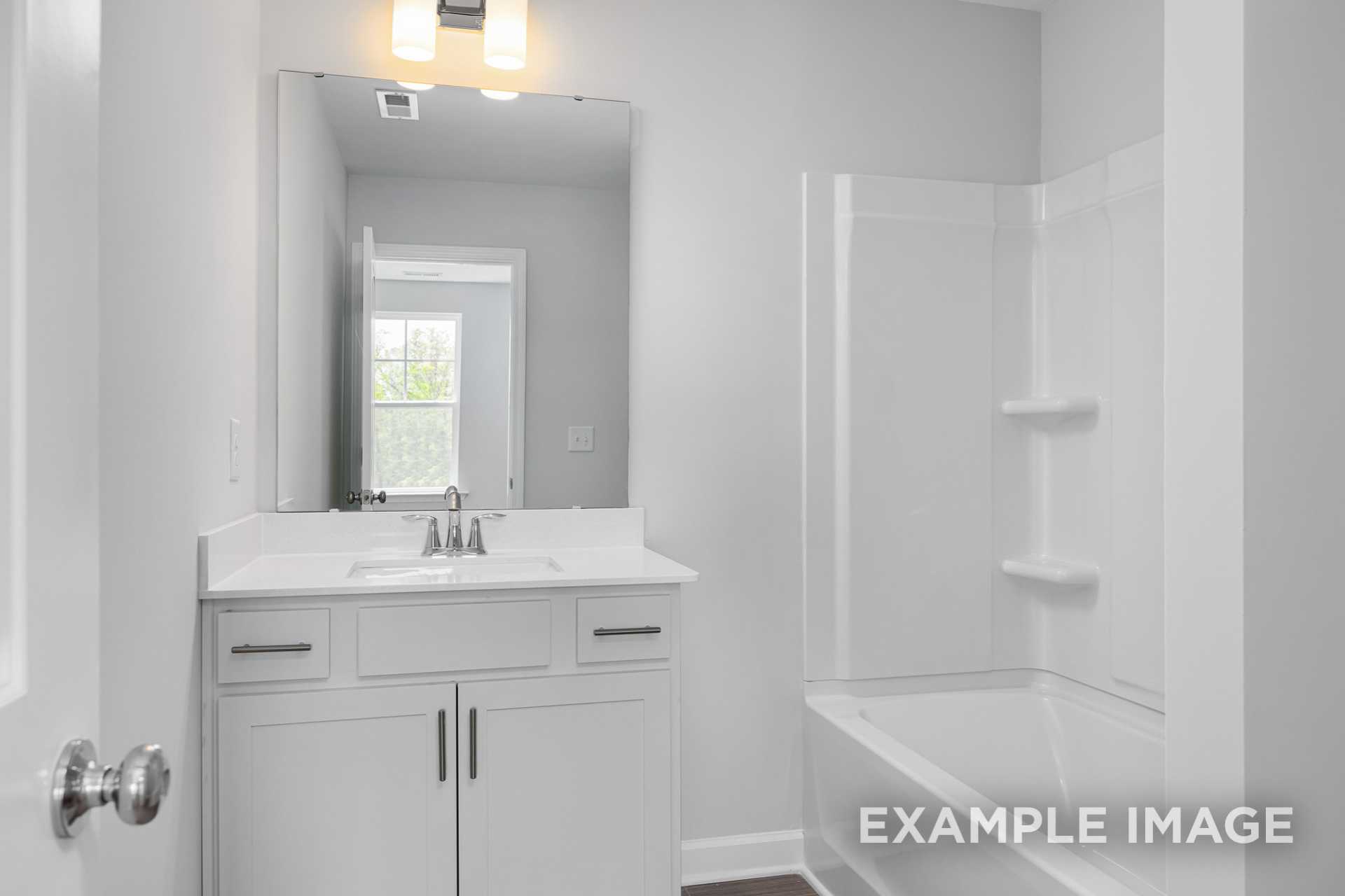 Spacious master bathroom in The Gavin C featuring white tiled shower, soaking tub, double vanity, and large mirror