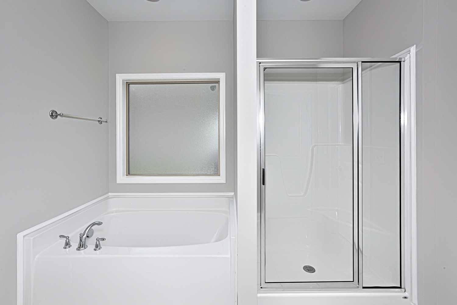 Master bathroom in The Montgomery with white soaking tub, chrome fixtures, and glass shower enclosure on gray walls