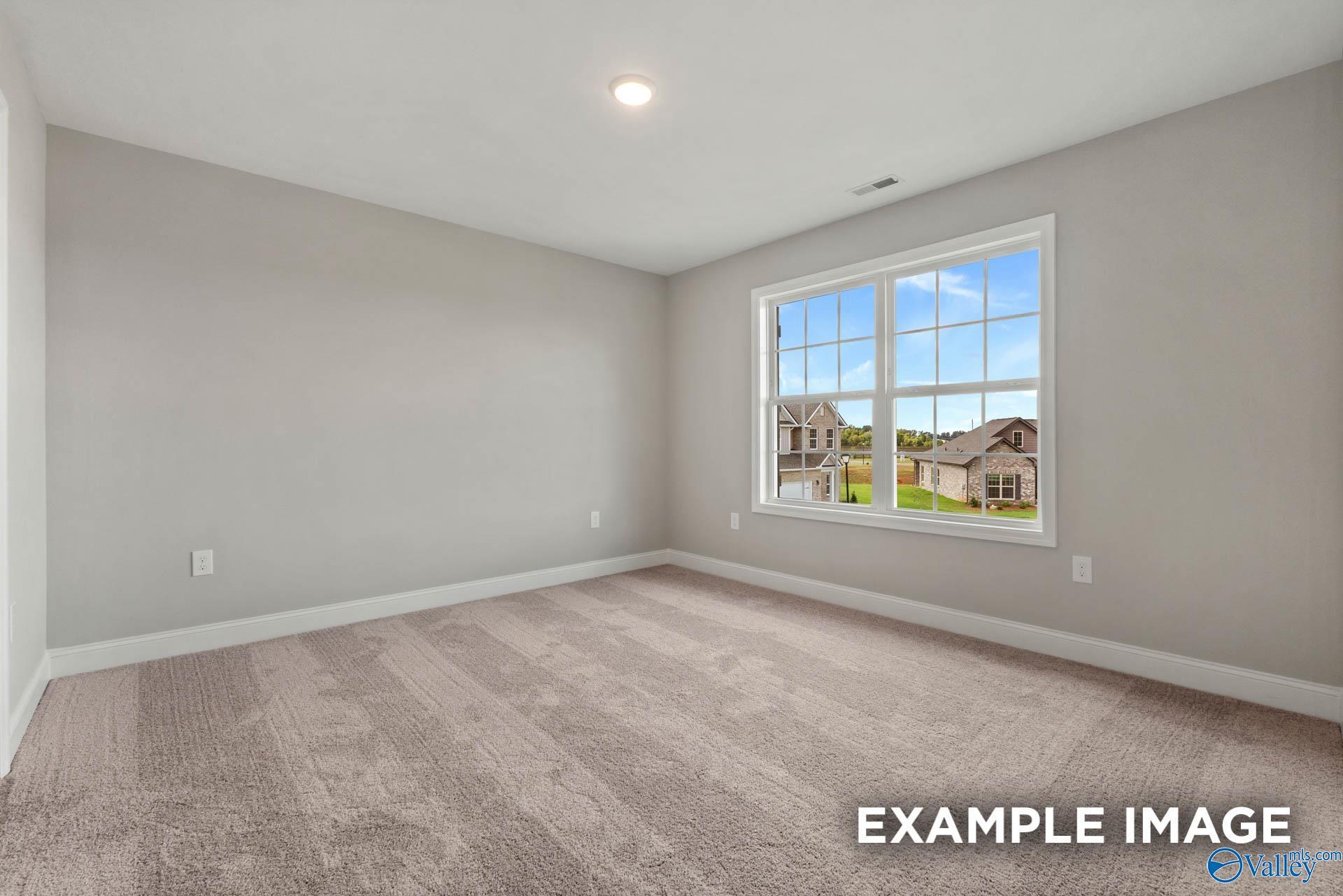 Bright empty bedroom with gray walls, carpeted floor, and large window overlooking Heritage Lakes neighborhood in Shelby B home, New Market, Alabama