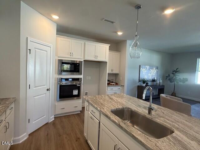 Modern kitchen with white cabinets, veined granite island, stainless double oven in Davidson Homes The Preston C, Lillington, NC
