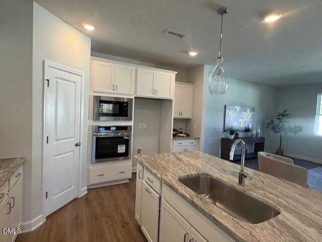 Modern white kitchen with granite countertops, stainless double oven, and island sink in Davidson Homes Preston C, Lillington, NC