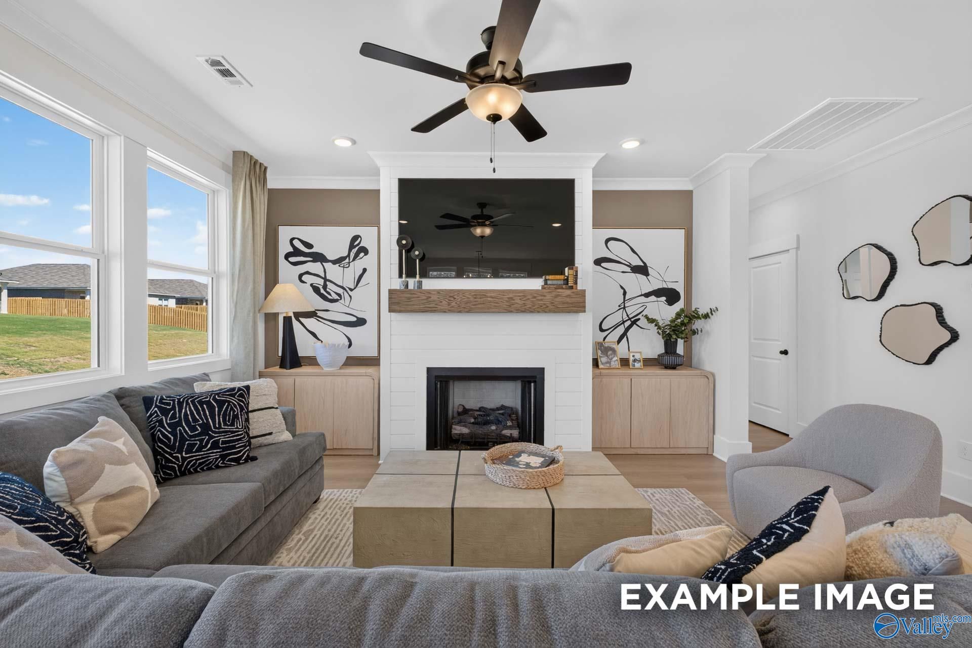 Bright great room with shiplap fireplace, mounted TV, and ceiling fan in The Ashport K model home at Forest Glen, Hazel Green, Alabama