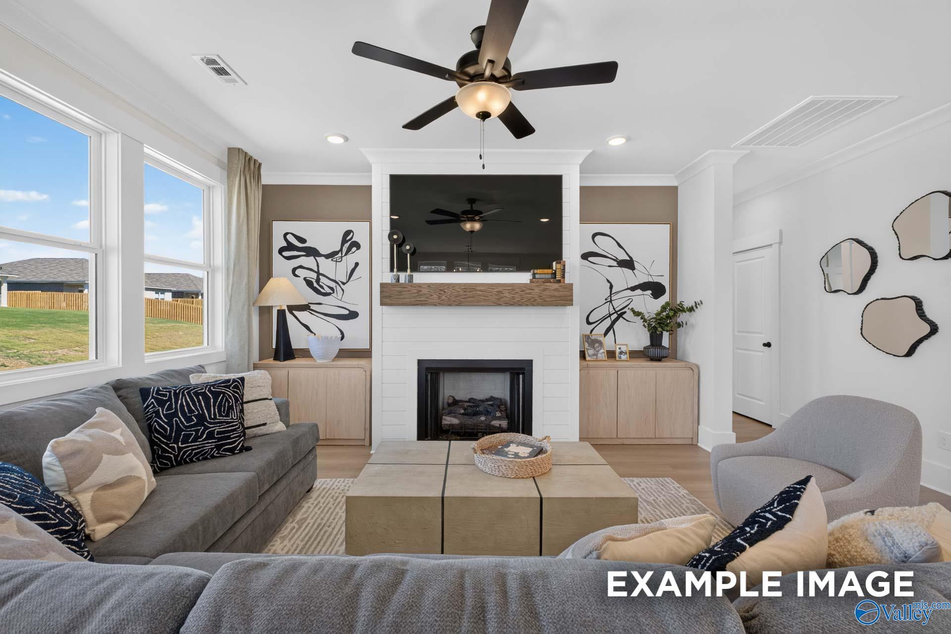 Bright great room with shiplap fireplace, mounted TV, and ceiling fan in The Ashport K model home at Forest Glen, Hazel Green, Alabama