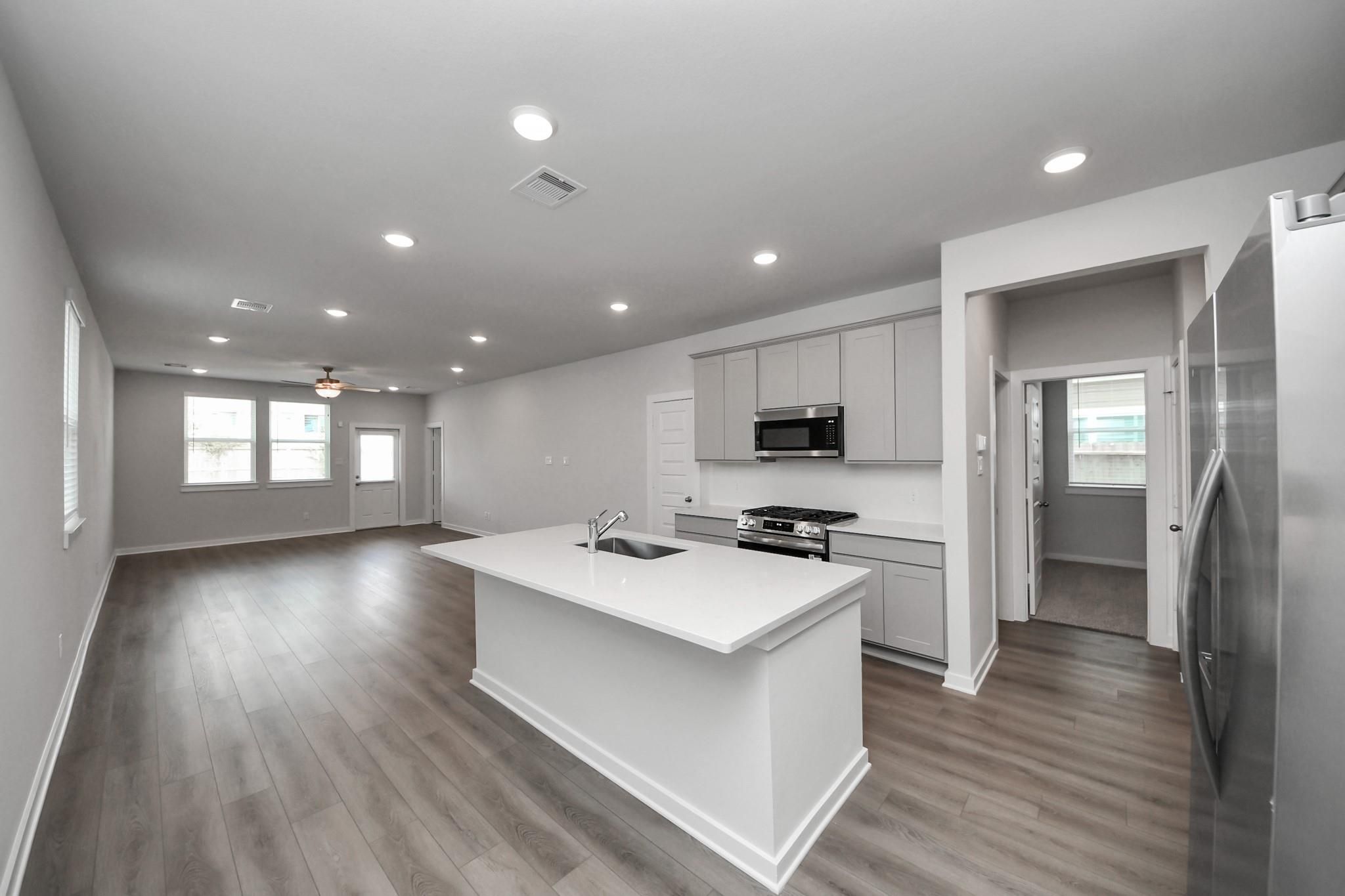 Open-concept kitchen with white island and grey cabinets in The Frio F floor plan at Robins Landing, Houston, Texas.