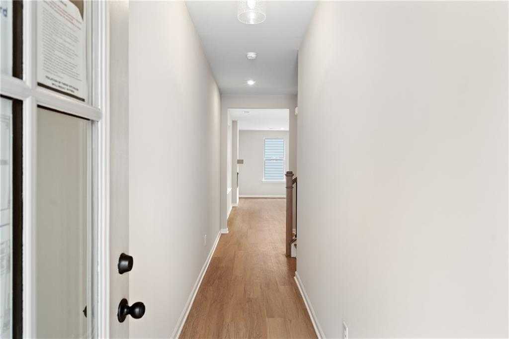 Bright hallway with light hardwood floors, white walls, and recessed lighting leading to staircase in The Marion A 3-bedroom home, Kennesaw, Georgia