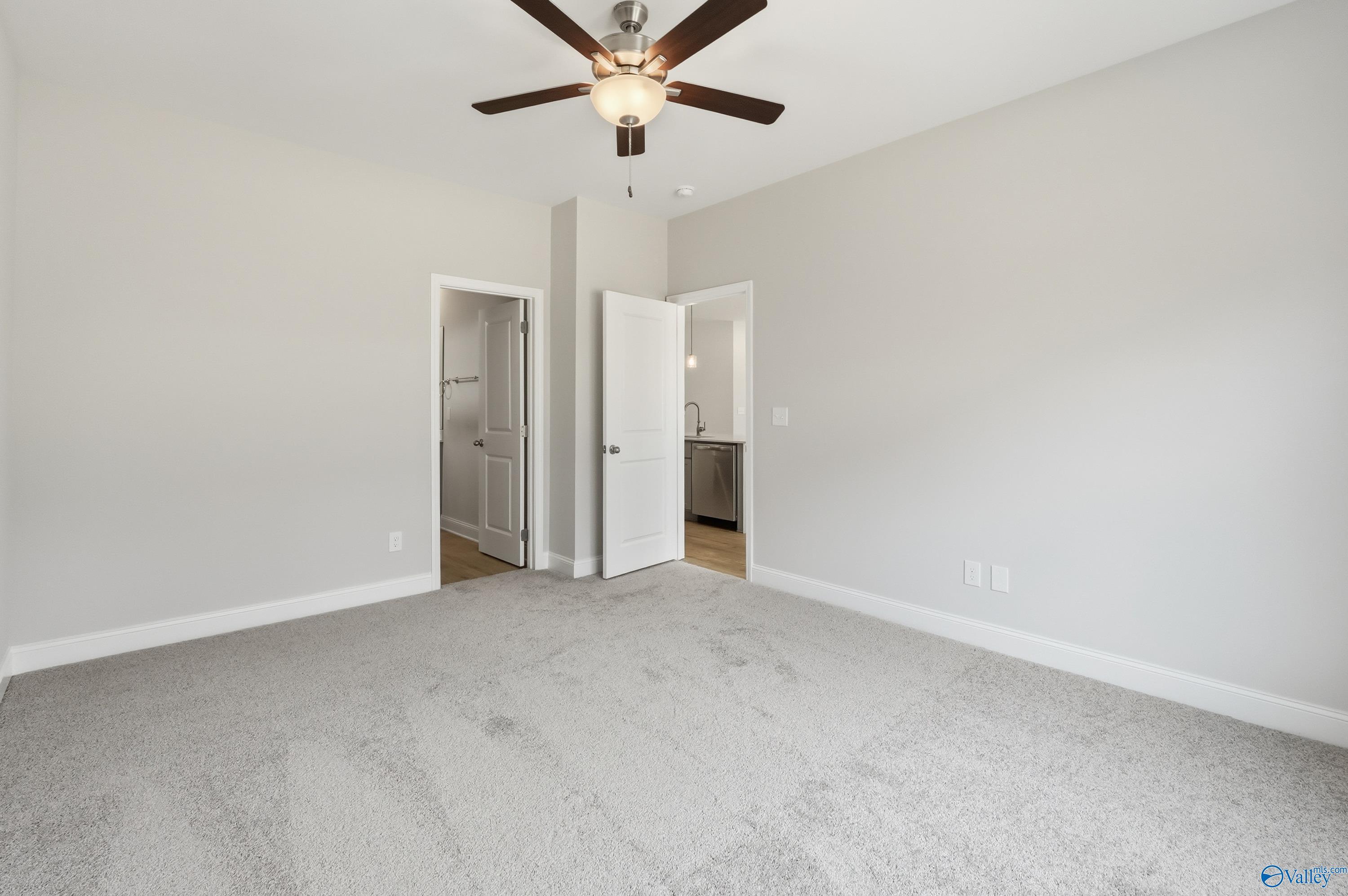 Spacious master bedroom with gray carpet, ceiling fan, and bathroom access in Davidson Homes The Franklin, Meridianville, Alabama