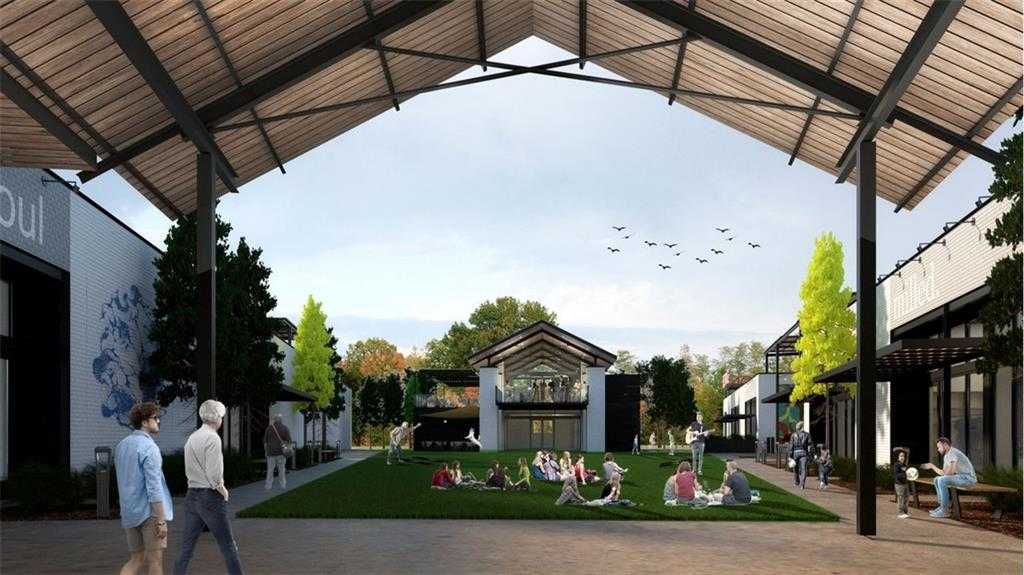 Vibrant open-air pavilion with wooden roof, people mingling on lush green lawn amid modern shops and trees in Wehunt Meadows, Hoschton, Georgia