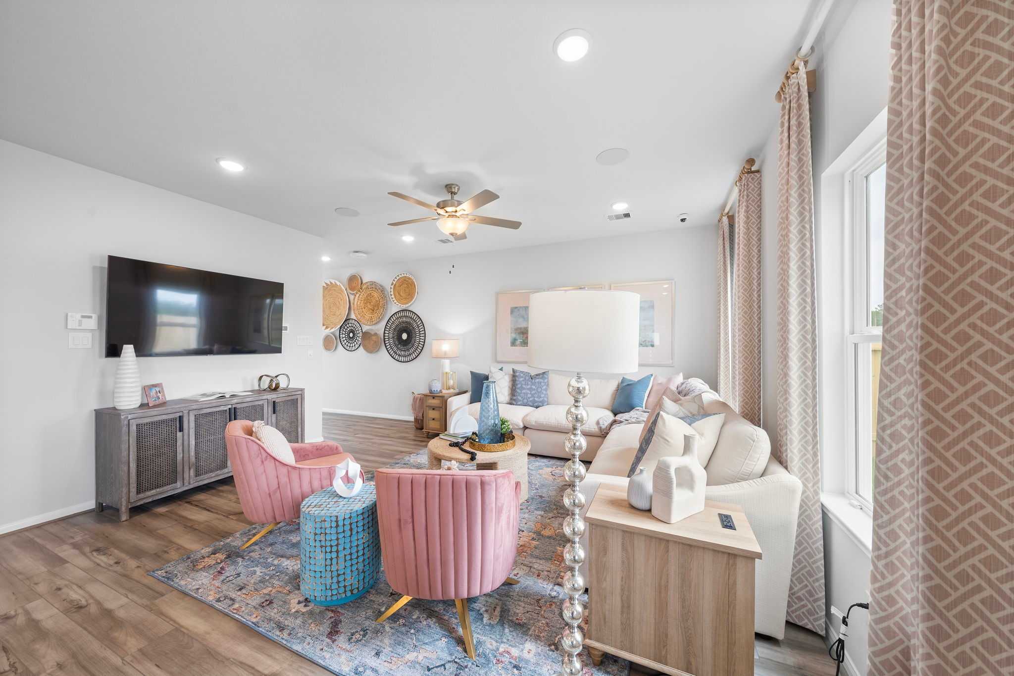 Cozy living room at Hill & Dale Ranch in Splendora Texas with white sectional sofa, pink armchairs, woven wall decor, hardwood floors
