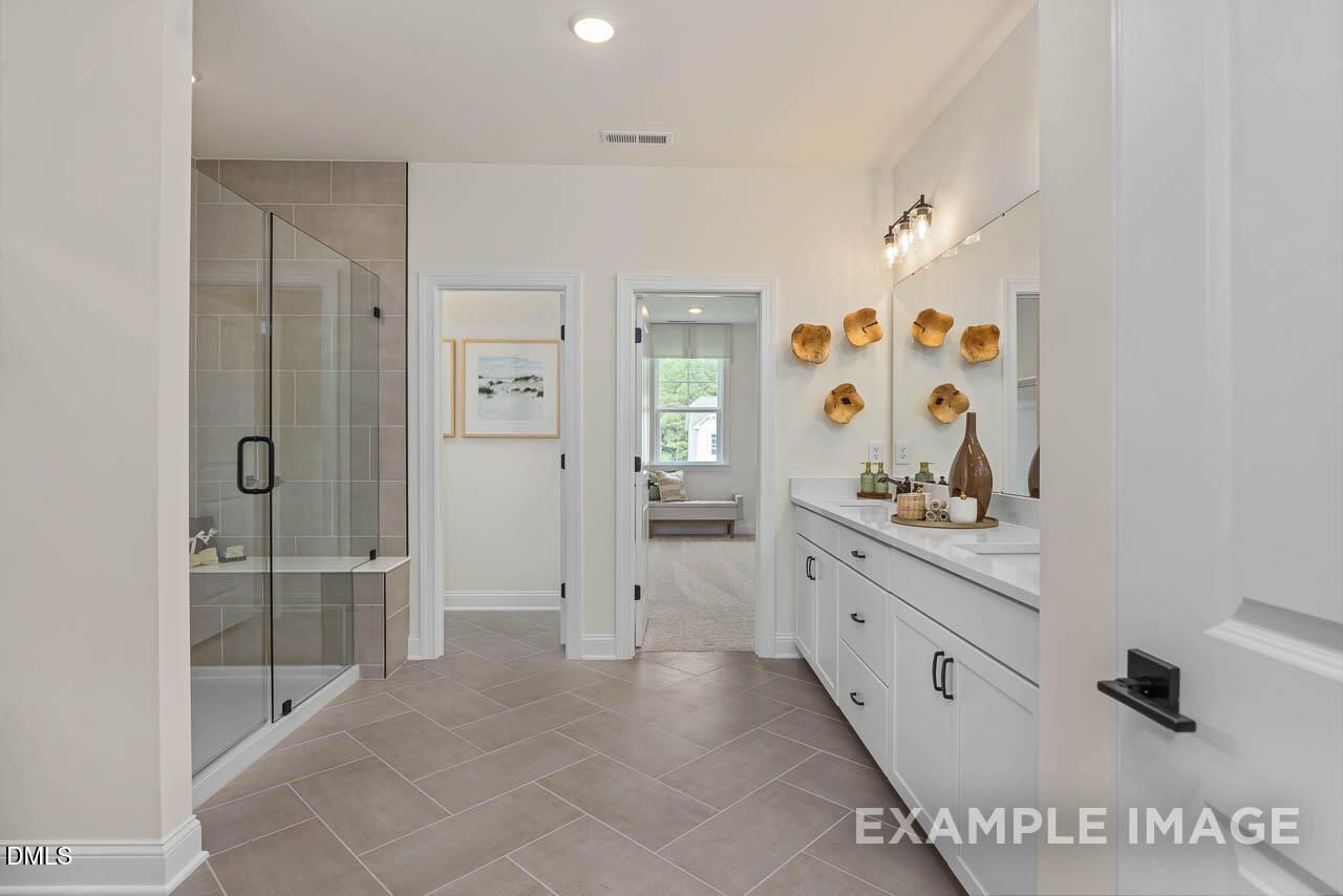 Elegant master bathroom with frameless glass shower, double vanity and modern decor in Davidson Homes The Crawford D, Angier, NC