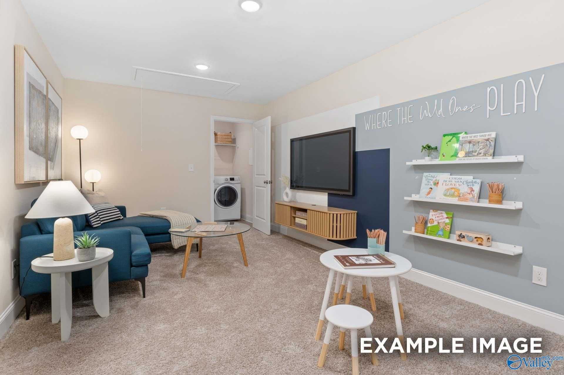 Cozy kids' playroom featuring navy sectional sofa, flat-screen TV, colorful bookshelves, and laundry nook in Davidson Homes The Camden B, Huntsville