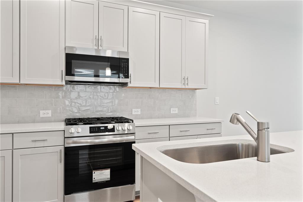 Contemporary kitchen with white shaker cabinets, stainless steel range, and quartz counters in Davidson Homes The Marion B, Kennesaw, GA