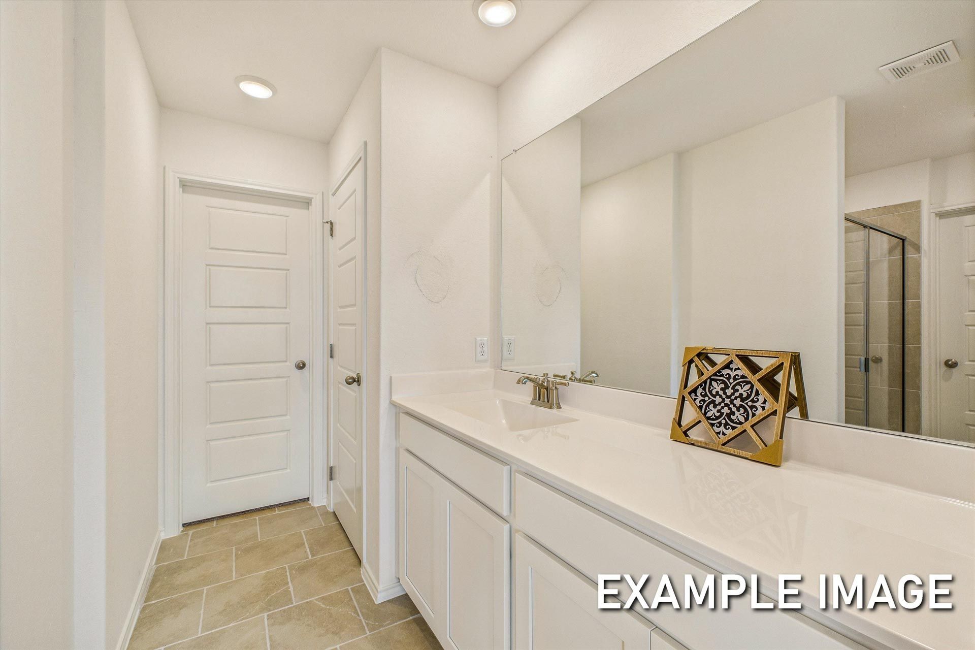 Spacious master bathroom in The Trinity B featuring white double vanity, large mirror, and tiled floor