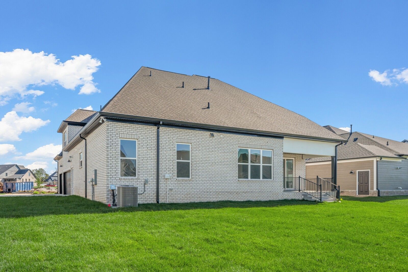 Two-story brick Hawkins home side view with covered patio, large windows, and green lawn in Shelton Square, Murfreesboro, Tennessee