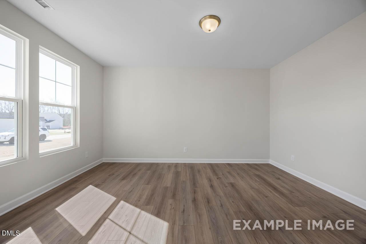 Bright empty living room with light hardwood floors, large windows, and natural light in Davidson Homes The Hickory II C, Lillington, NC