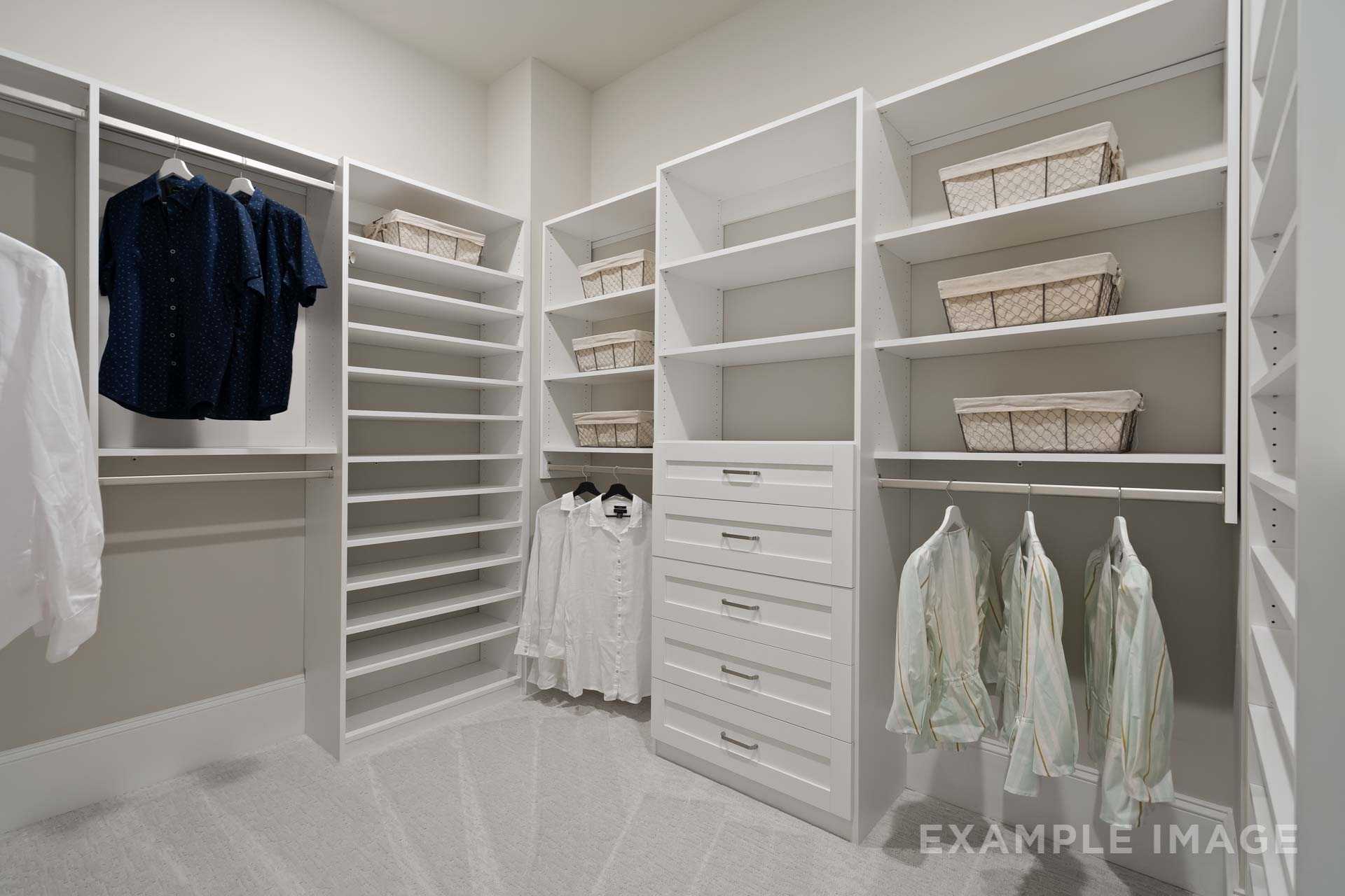 Spacious master walk-in closet in The Seaside by Davidson Homes with white built-ins, hanging rods, and wicker baskets