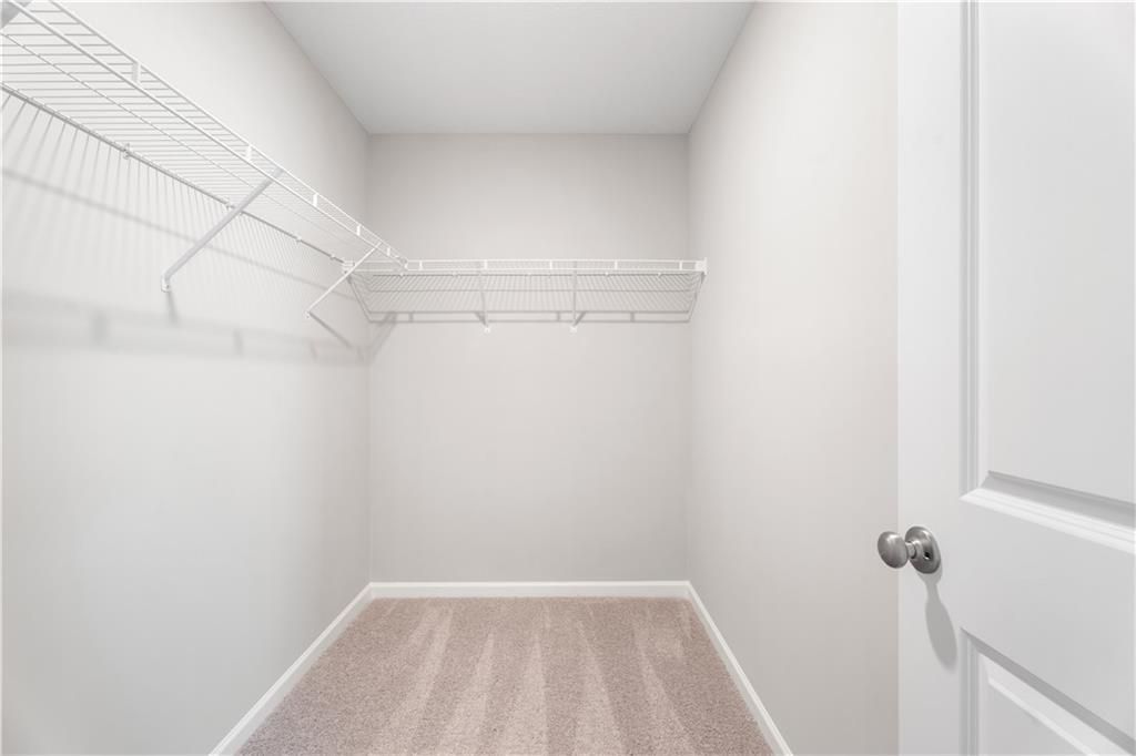 Walk-in closet with white wire shelving and plush carpet in The Washington floor plan at Summer Vineyard, Phenix City, AL.