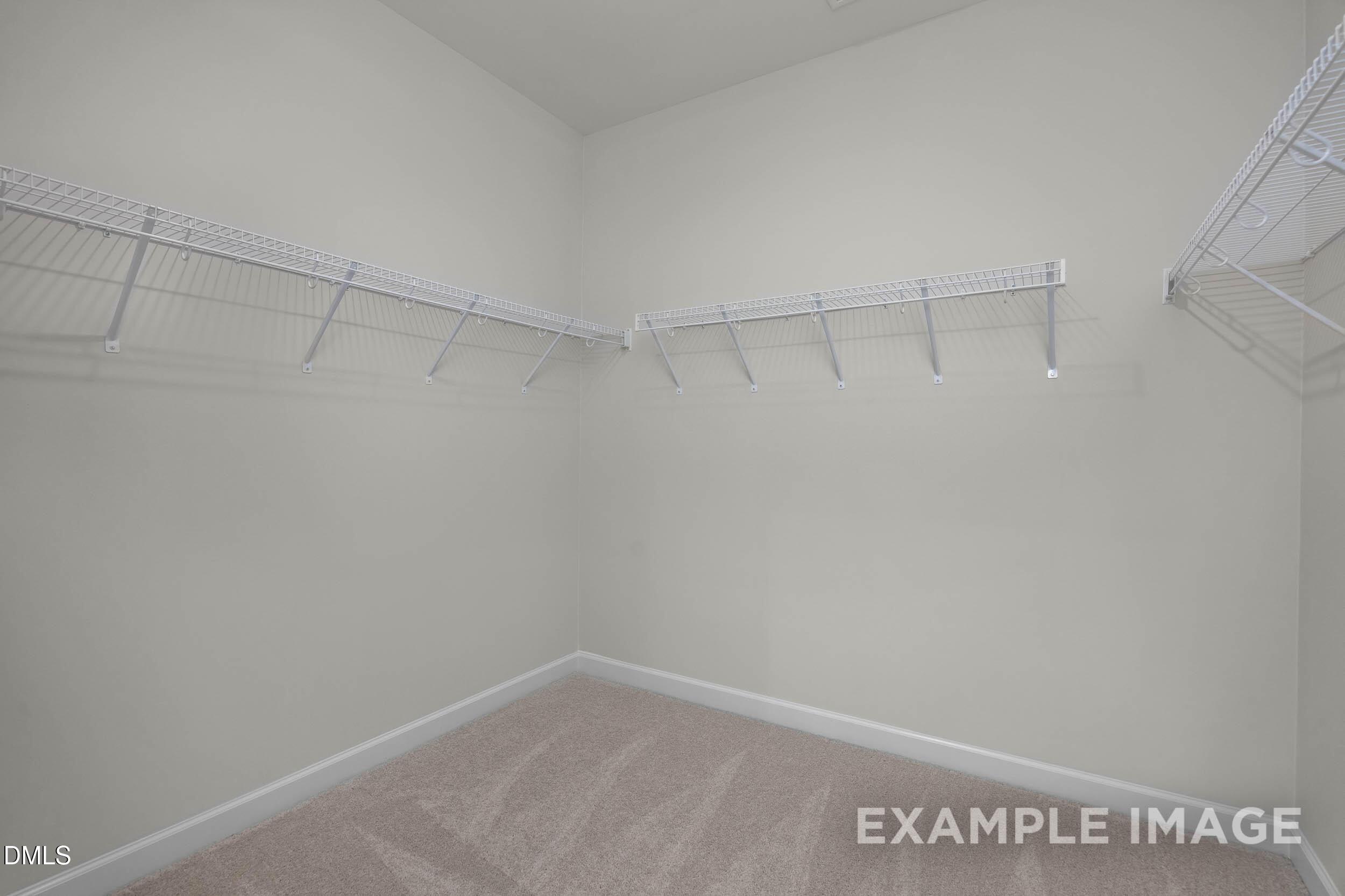 Walk-in closet with white wire shelving and carpeted floors in The Franklin C floor plan at Retreat at North Main.