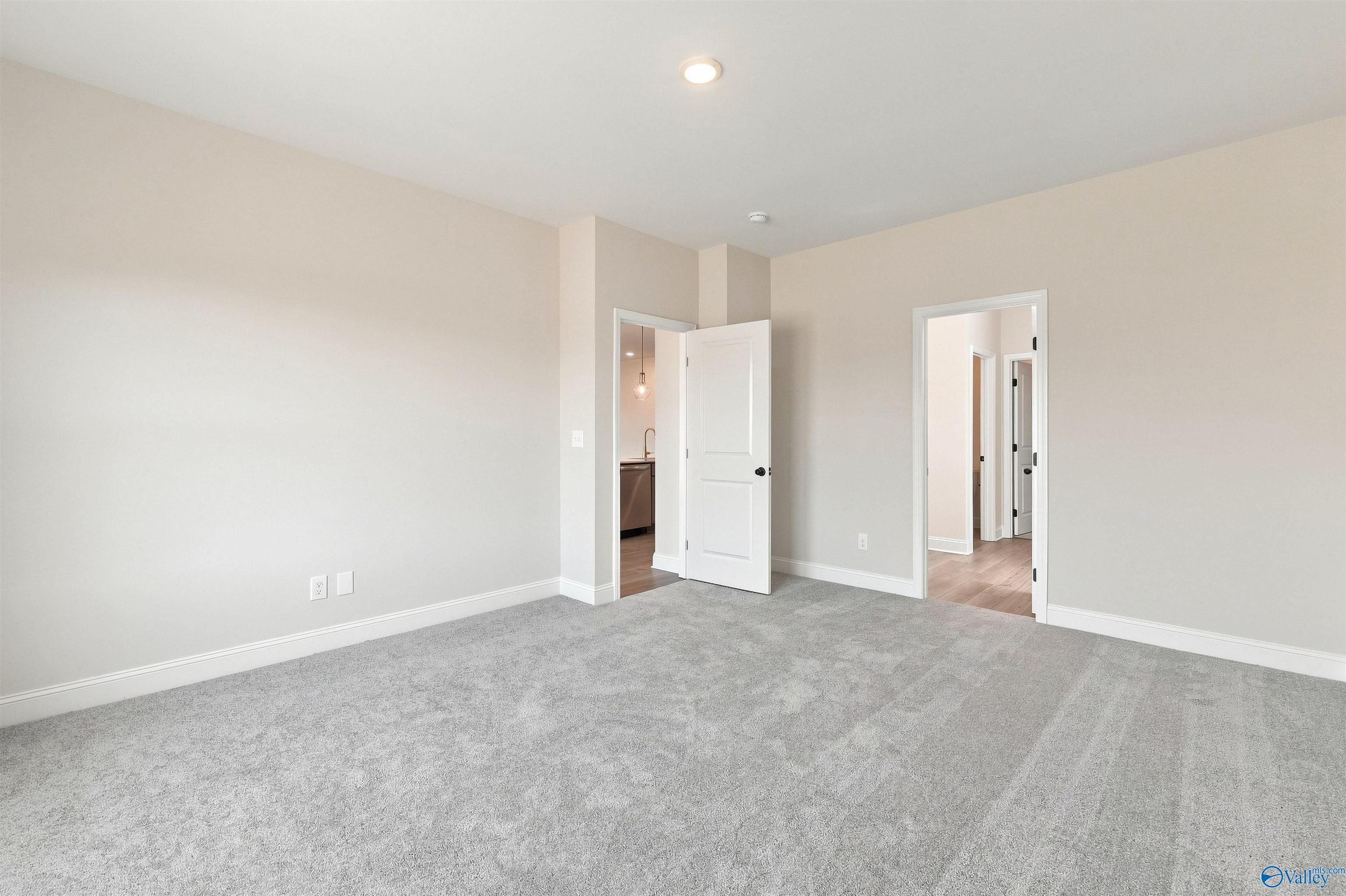 Spacious carpeted bedroom with white doors and neutral walls in Davidson Homes The Everett B, Ivy Hills, Toney, Alabama