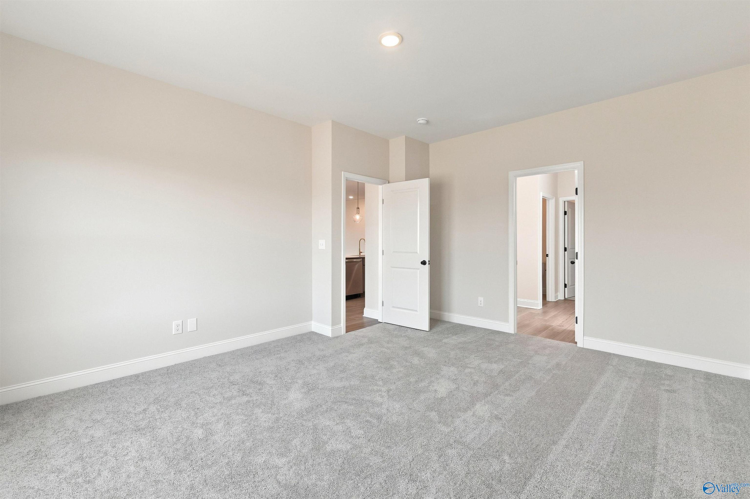 Spacious carpeted bedroom with white doors and neutral walls in Davidson Homes The Everett B, Ivy Hills, Toney, Alabama