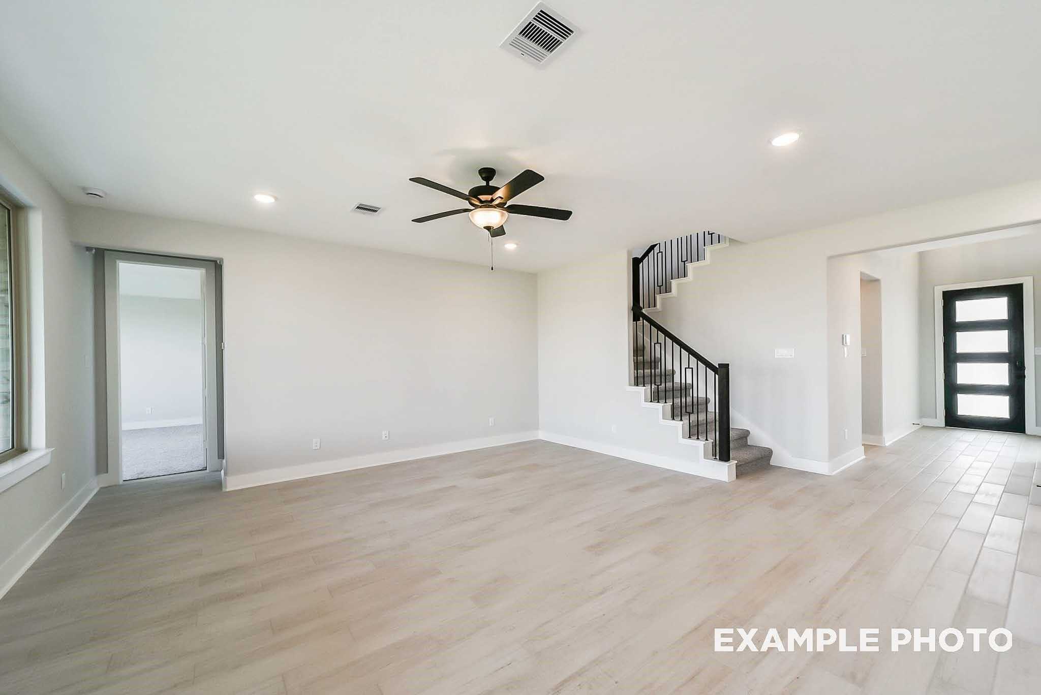 Spacious entry foyer with curved staircase, ceiling fan, and luxury vinyl plank floors in Davidson Homes The Philip C, Rosharon, TX