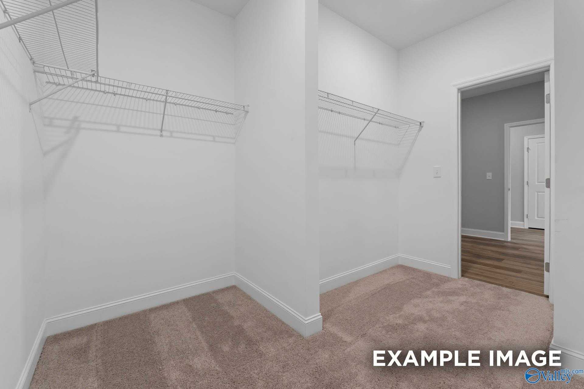 Spacious walk-in closet with wire shelving and hanging rods in master suite of Davidson Homes The Everett, Meridianville, Alabama