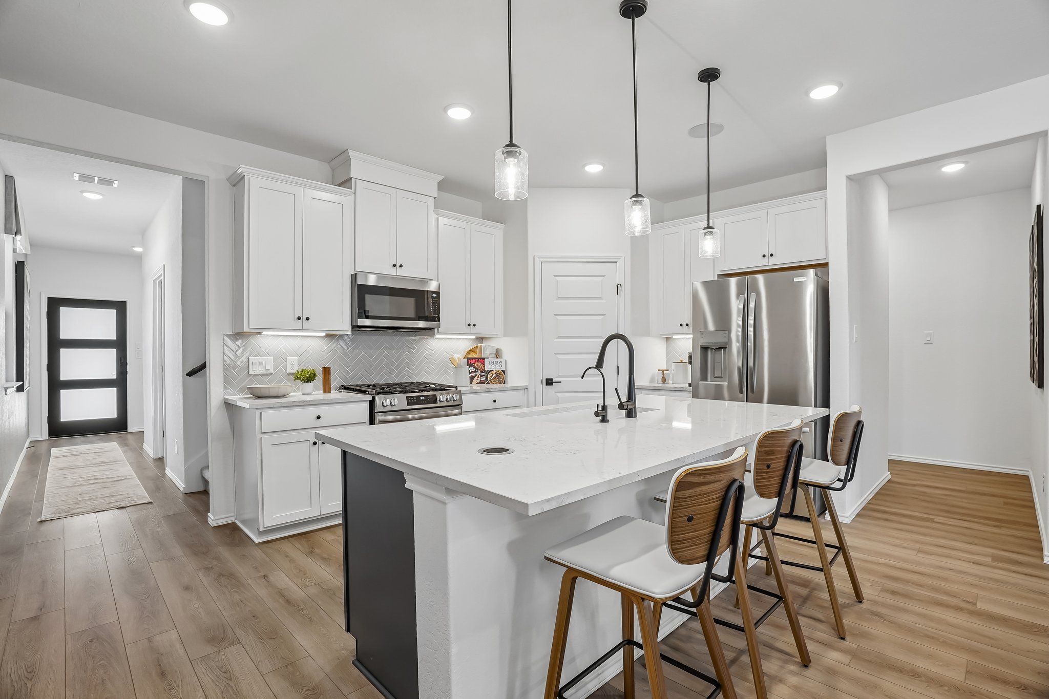 Modern kitchen with white cabinets, quartz island, and stainless steel appliances at Fairway Crossing in Converse, Texas.