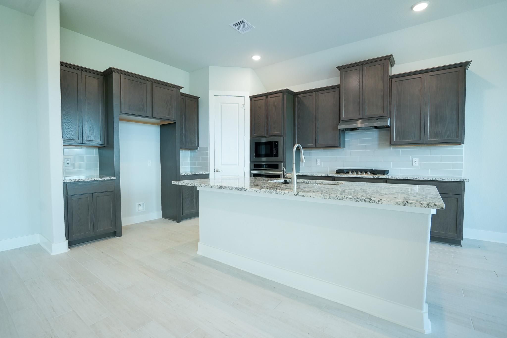 Modern shaker kitchen with granite island, stainless appliances in Davidson Homes The Edward C, Lago Mar, Texas City