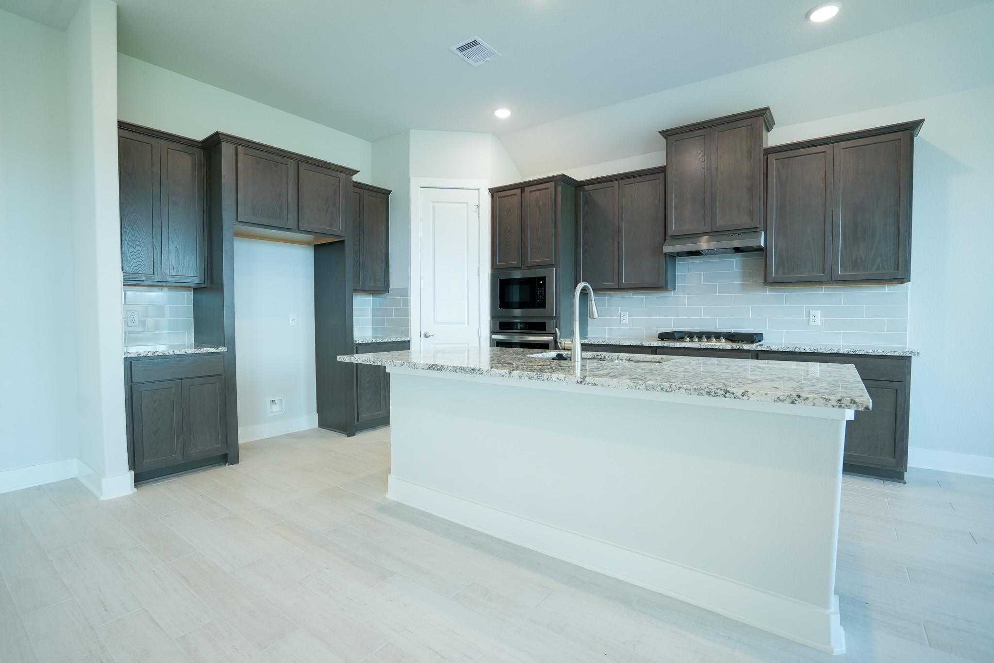 Modern shaker kitchen with granite island, stainless appliances in Davidson Homes The Edward C, Lago Mar, Texas City